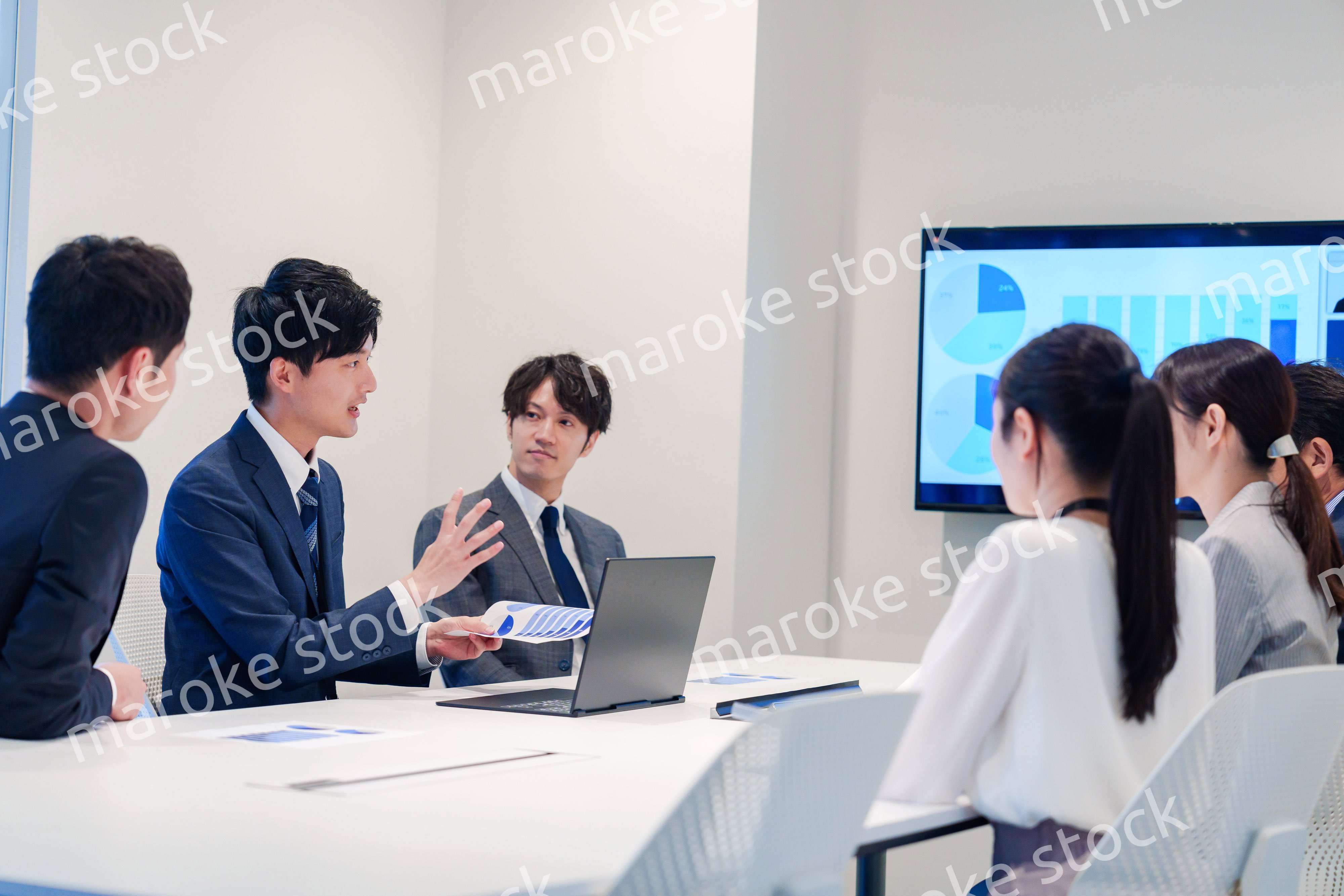 スーツを着て会議で話す若い男性