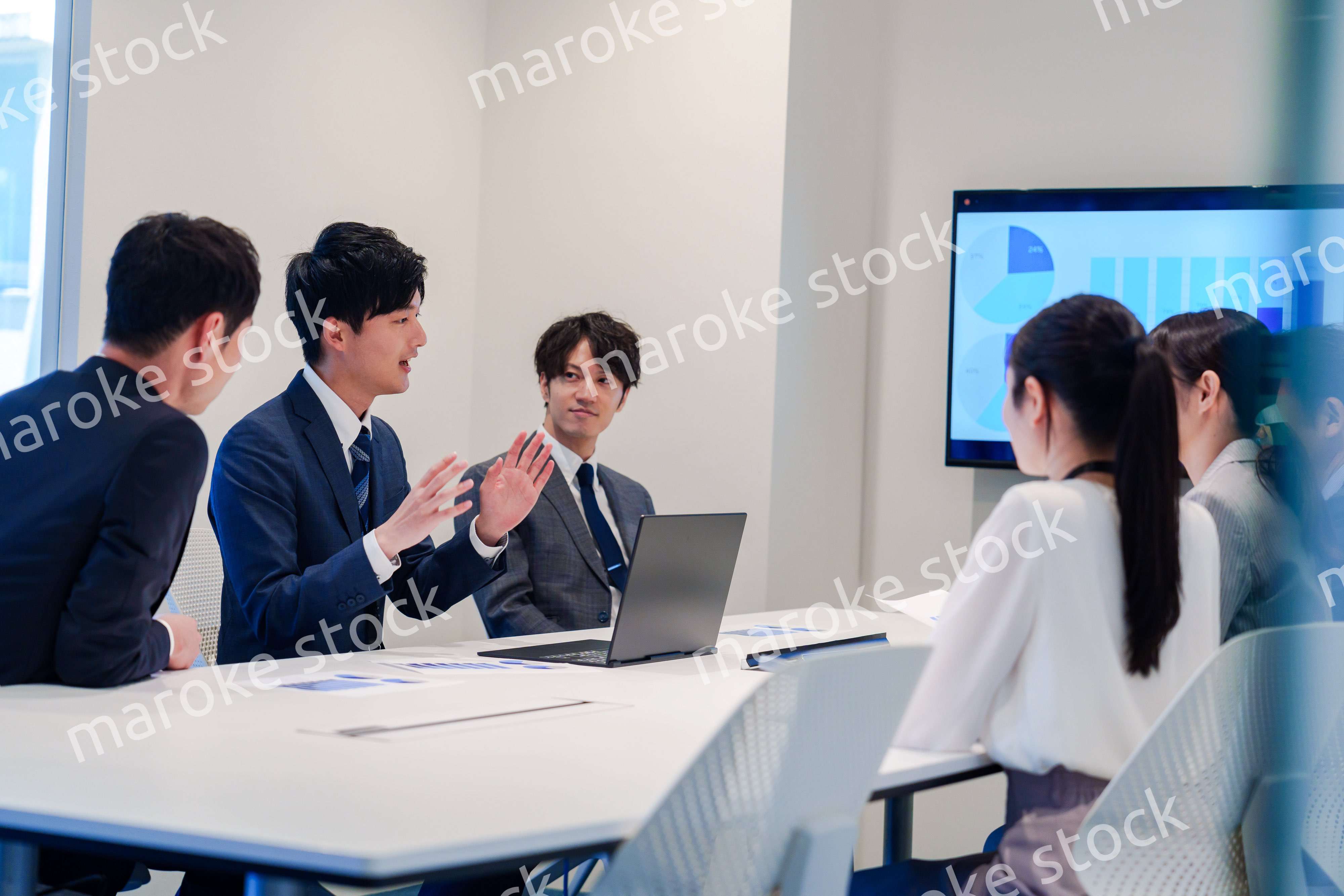 スーツを着て会議で話す若い男性