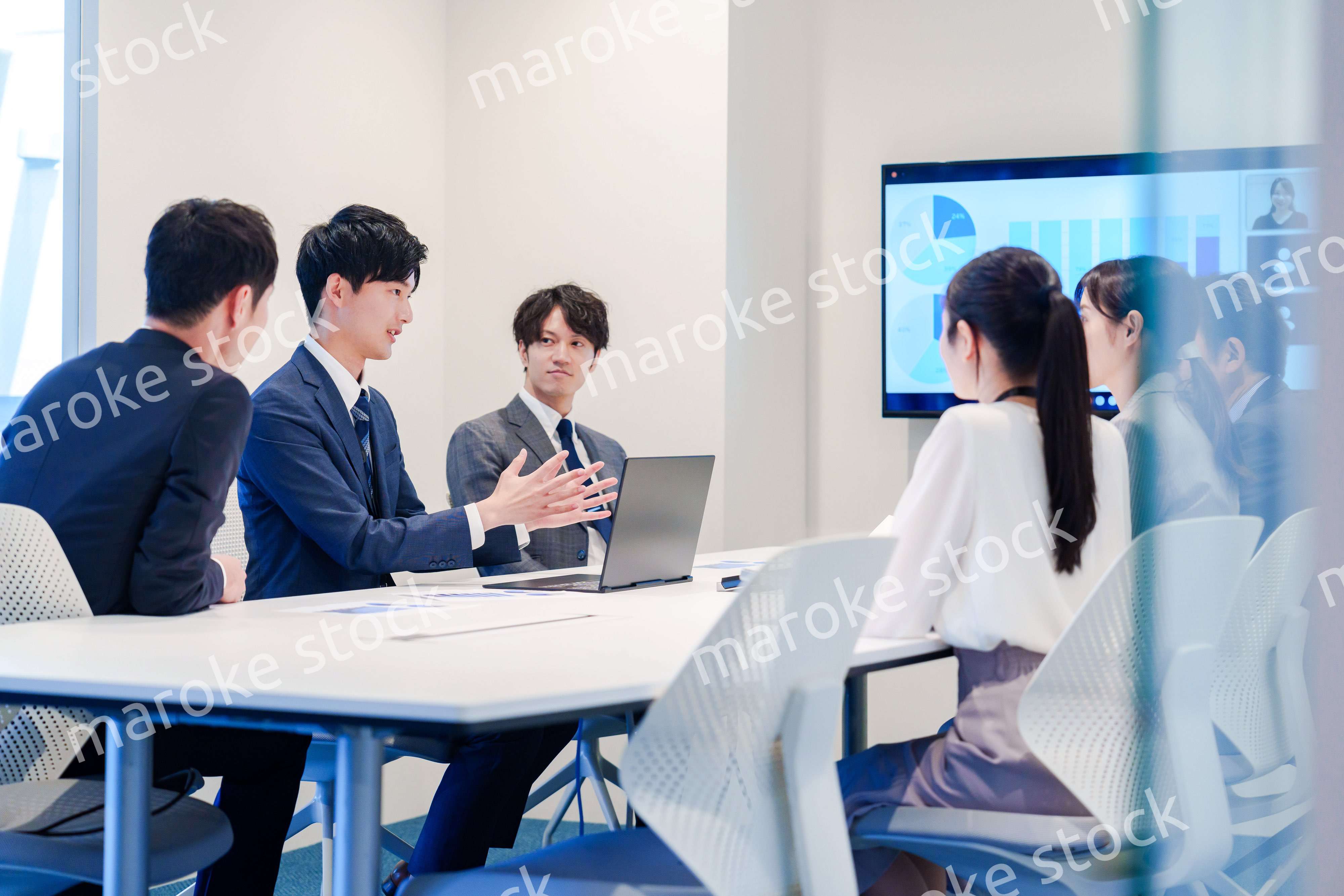 スーツを着て会議で話す若い男性