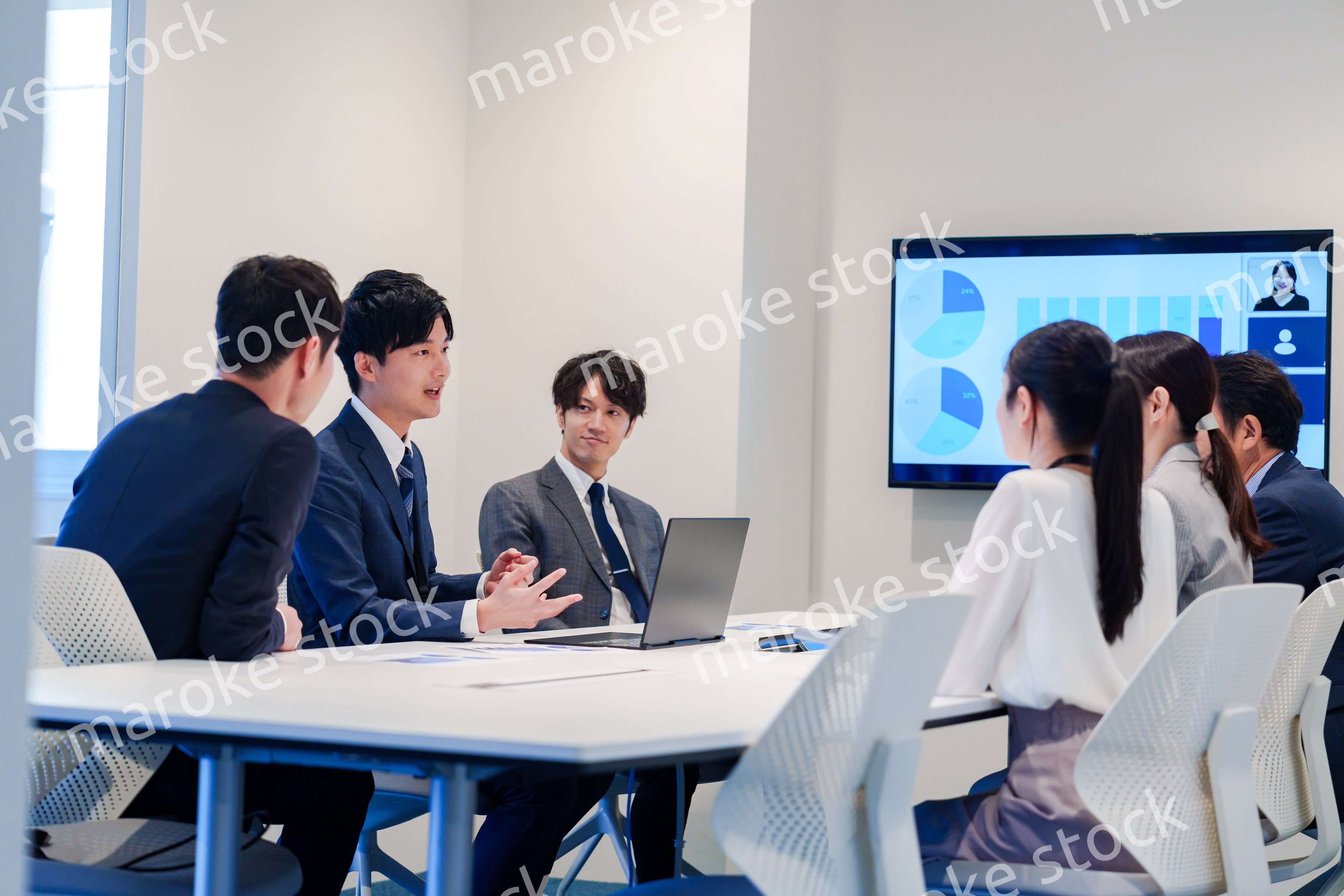 スーツを着て会議で話す若い男性