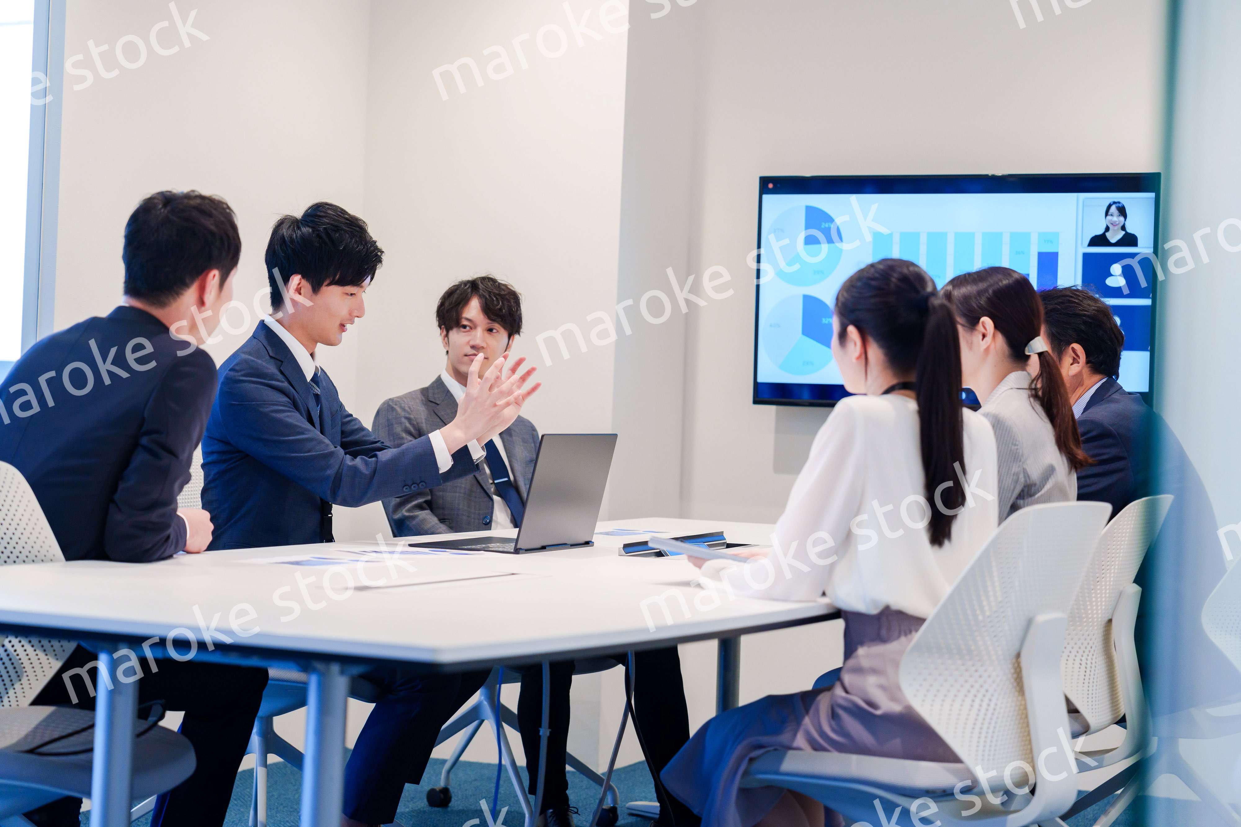 スーツを着て会議で話す若い男性