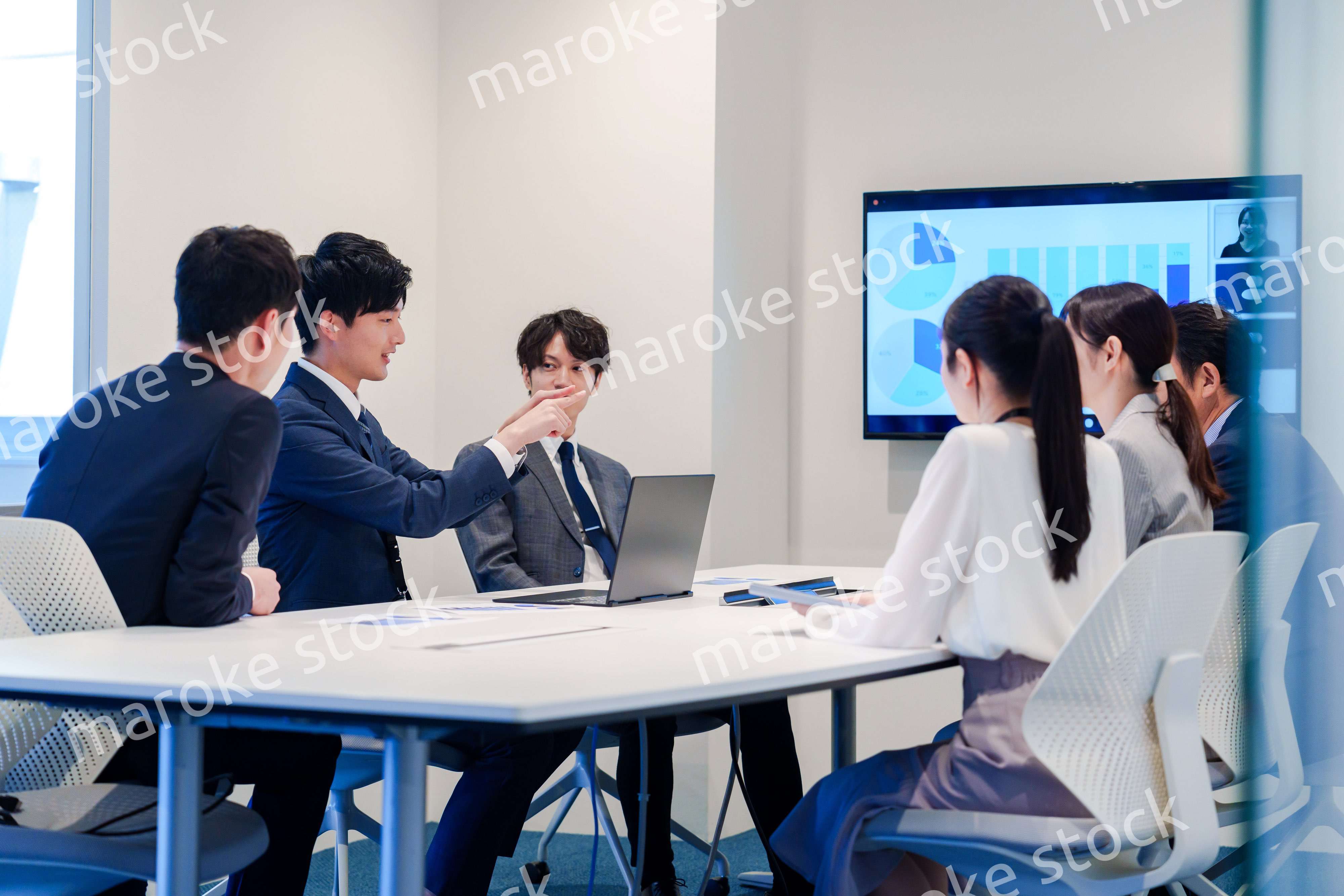 スーツを着て会議で話す若い男性