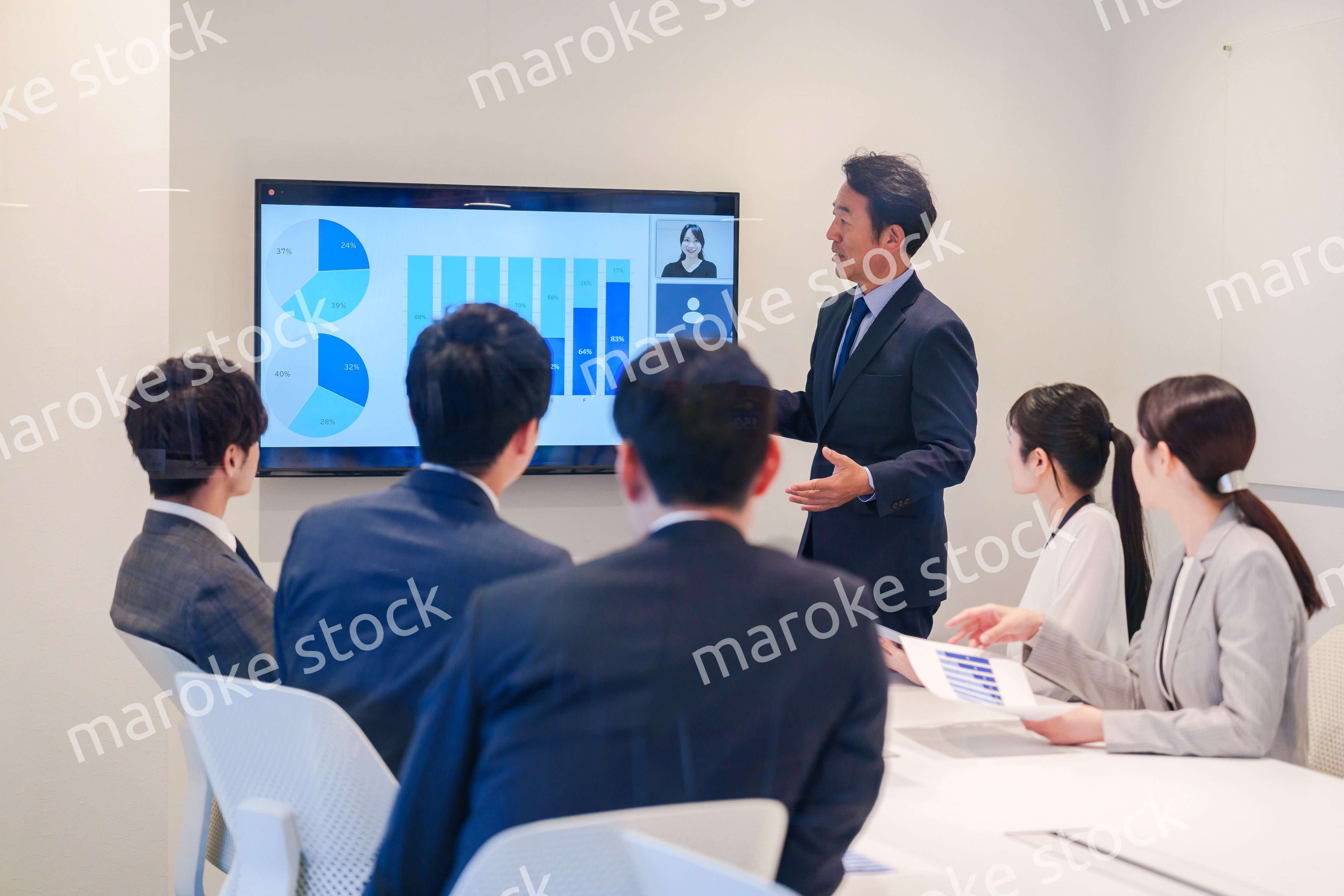 会議で資料を見ながらプレゼンをする中年のオフィスワーカー