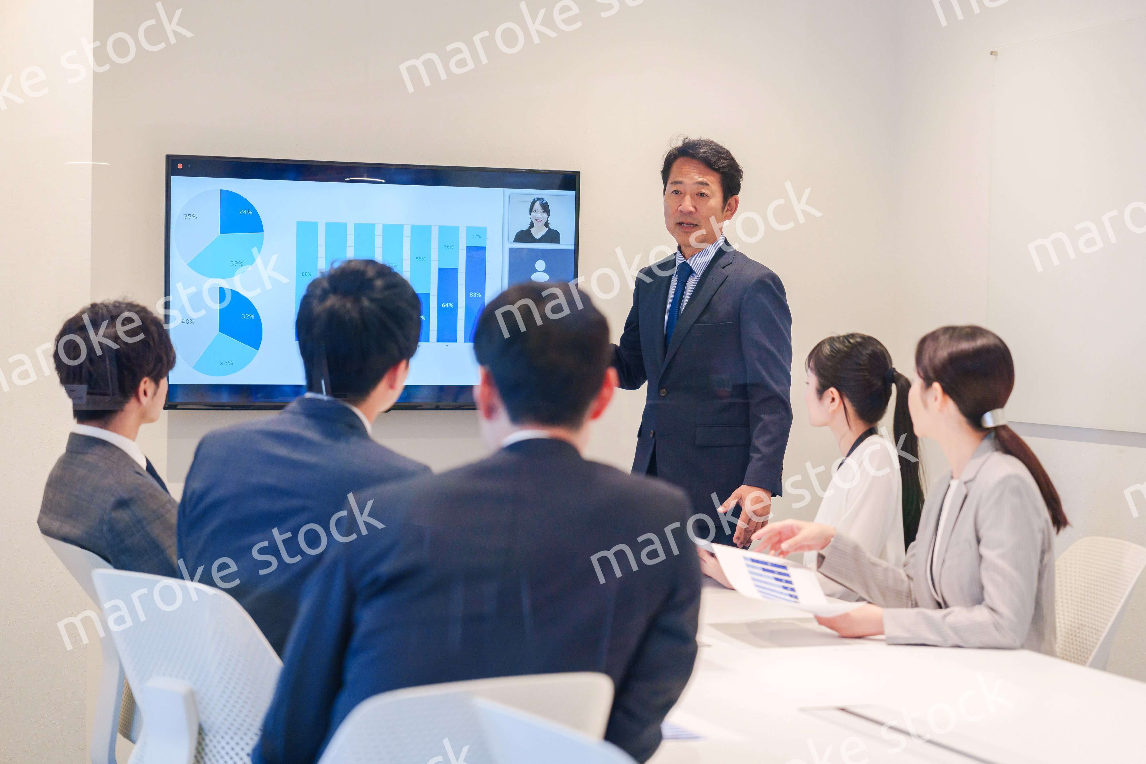 会議で資料を見ながらプレゼンをする中年のオフィスワーカー