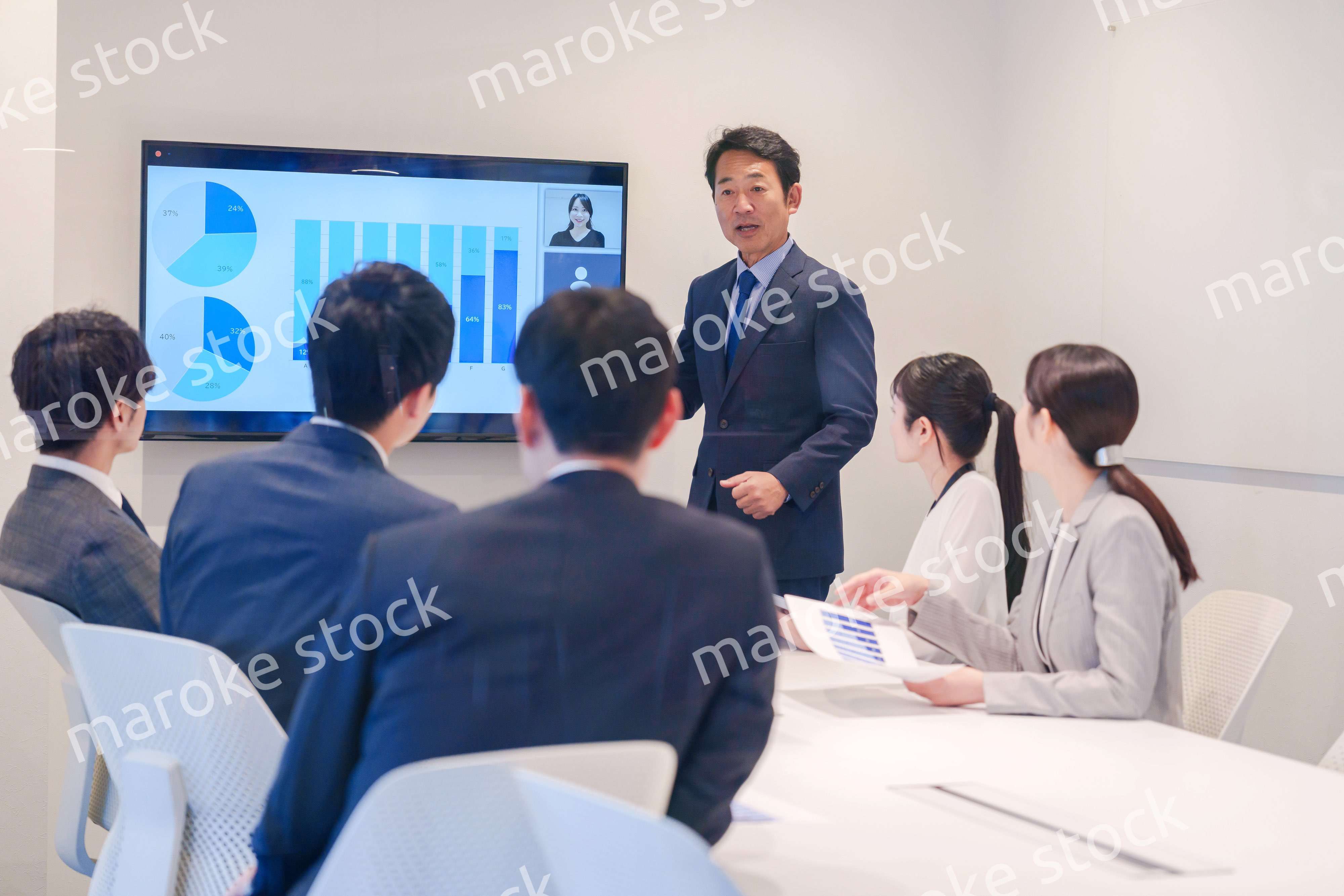 会議で資料を見ながらプレゼンをする中年のオフィスワーカー