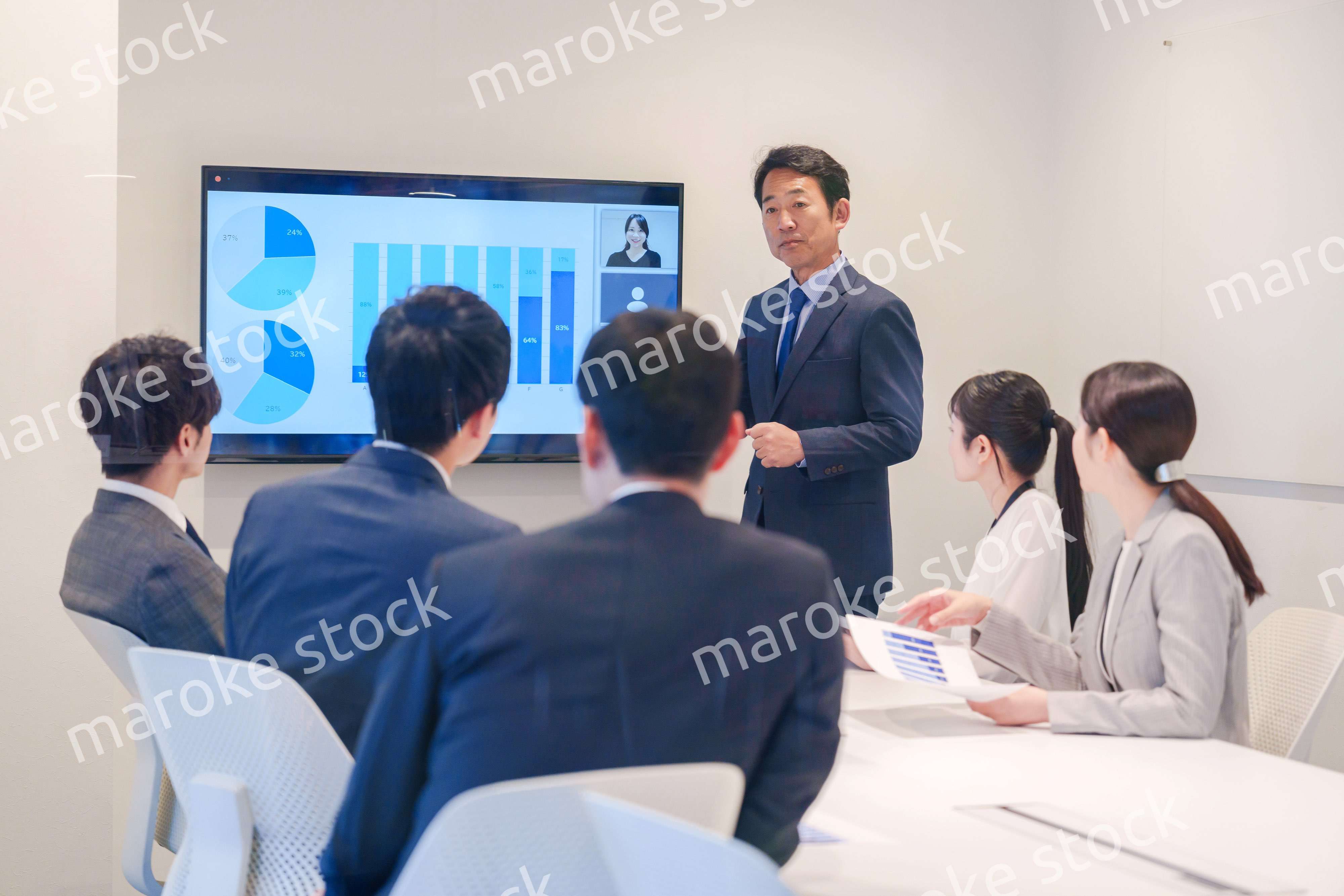 会議で資料を見ながらプレゼンをする中年のオフィスワーカー