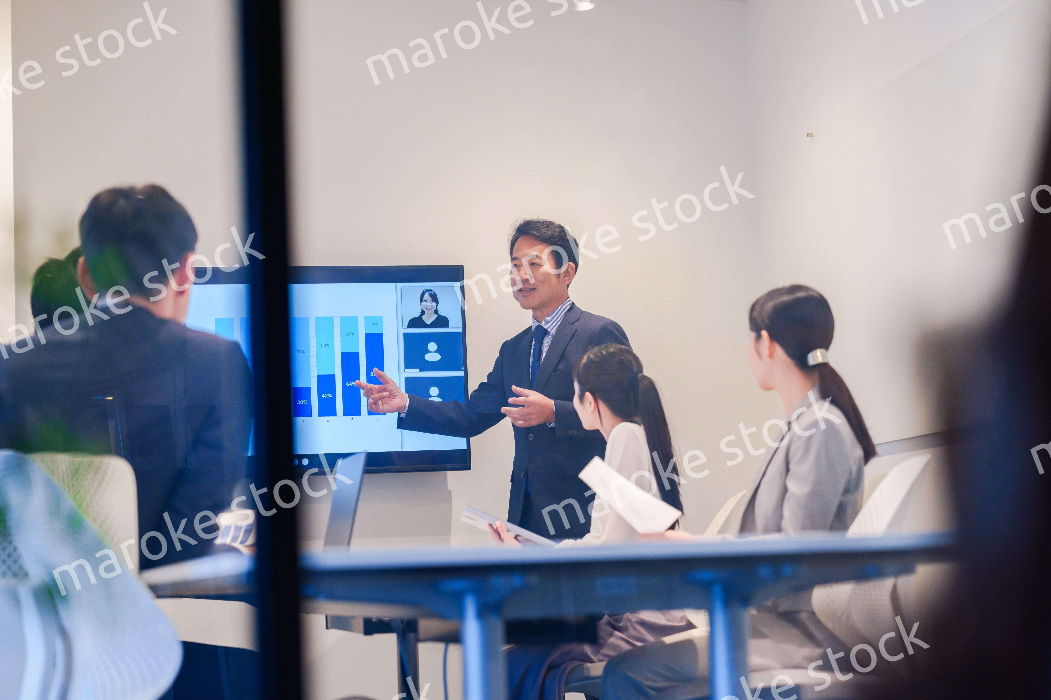 会議で資料を見ながらプレゼンをする中年のオフィスワーカー