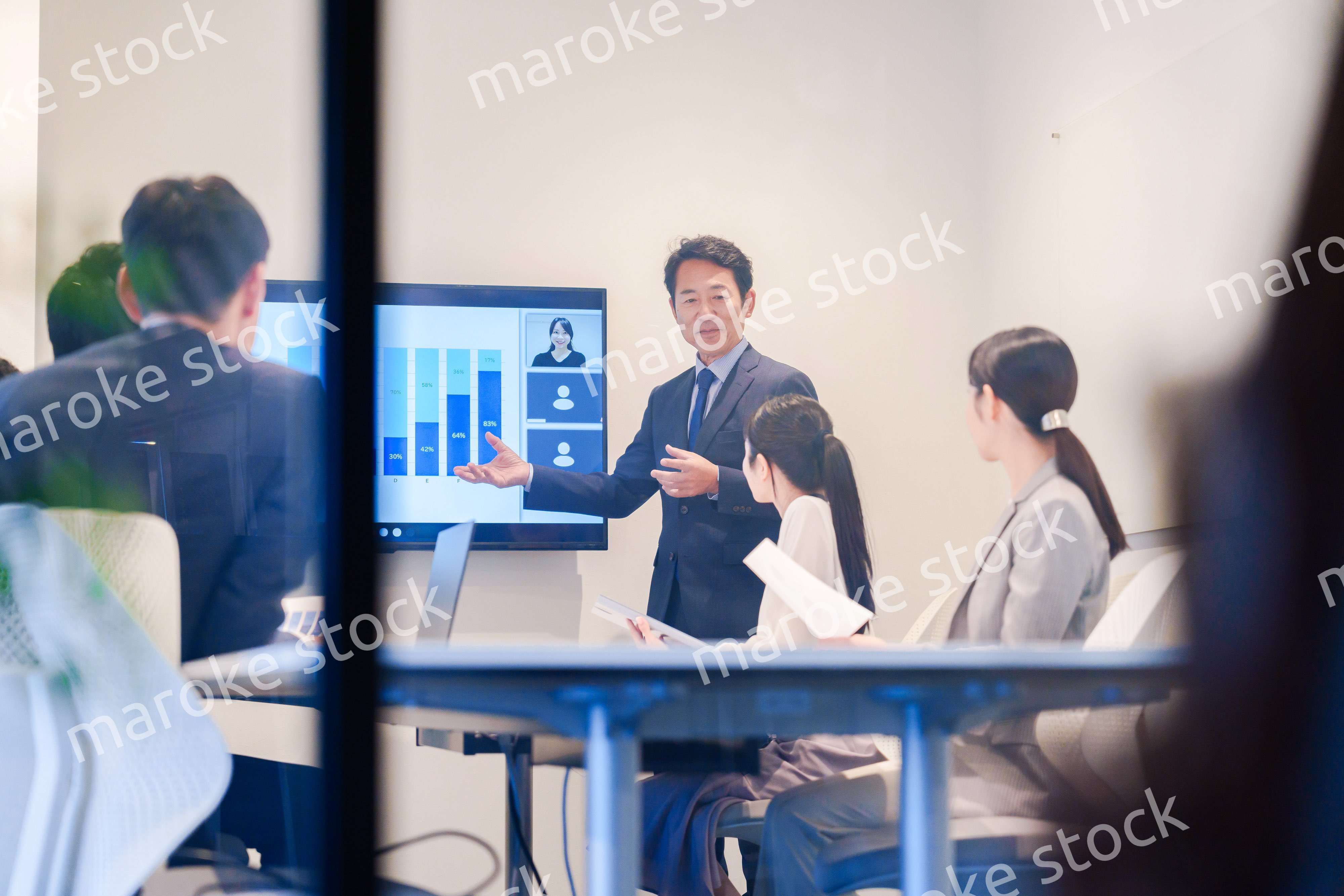 会議で資料を見ながらプレゼンをする中年のオフィスワーカー