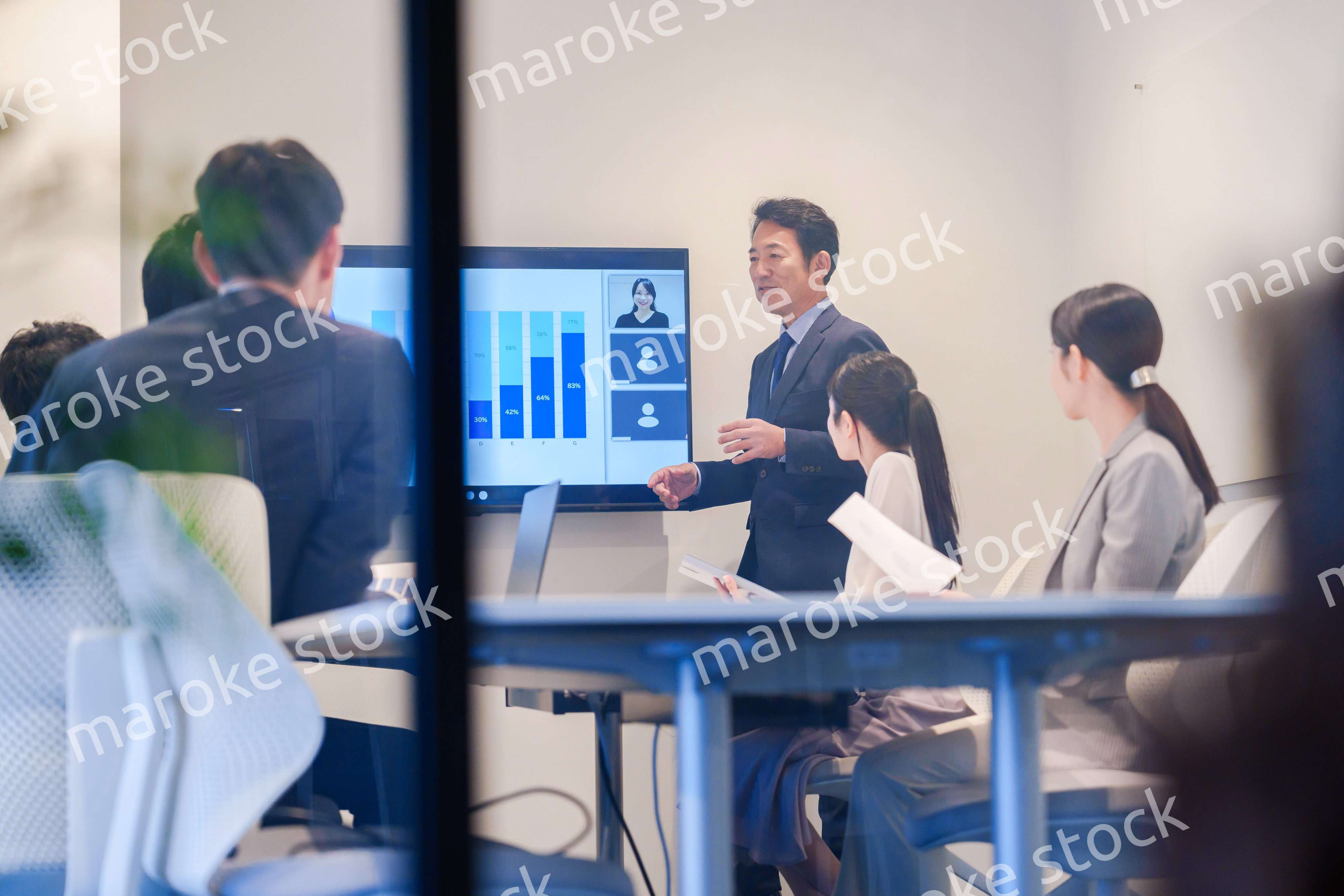 会議で資料を見ながらプレゼンをする中年のオフィスワーカー