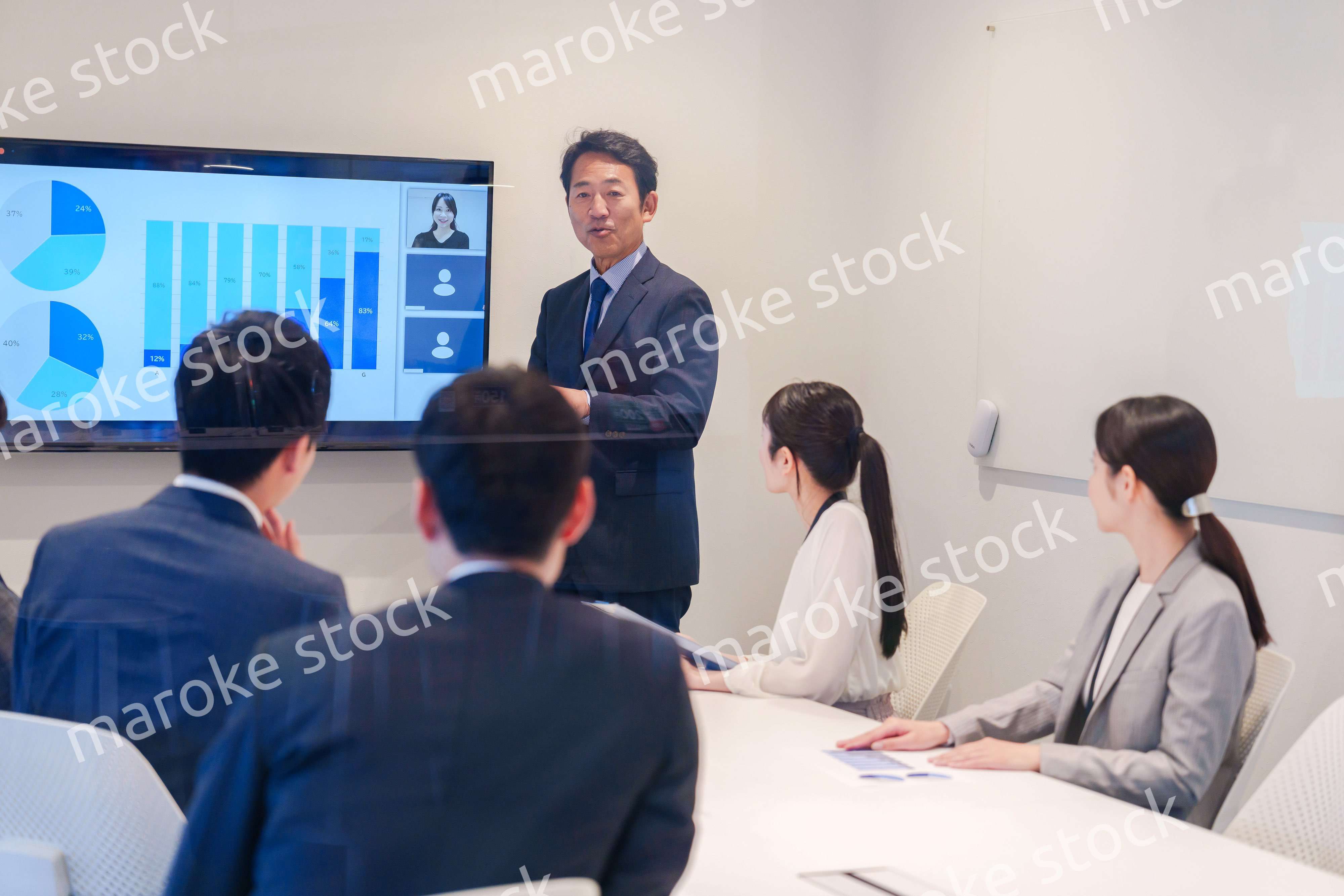 会議で資料を見ながらプレゼンをする中年のオフィスワーカー