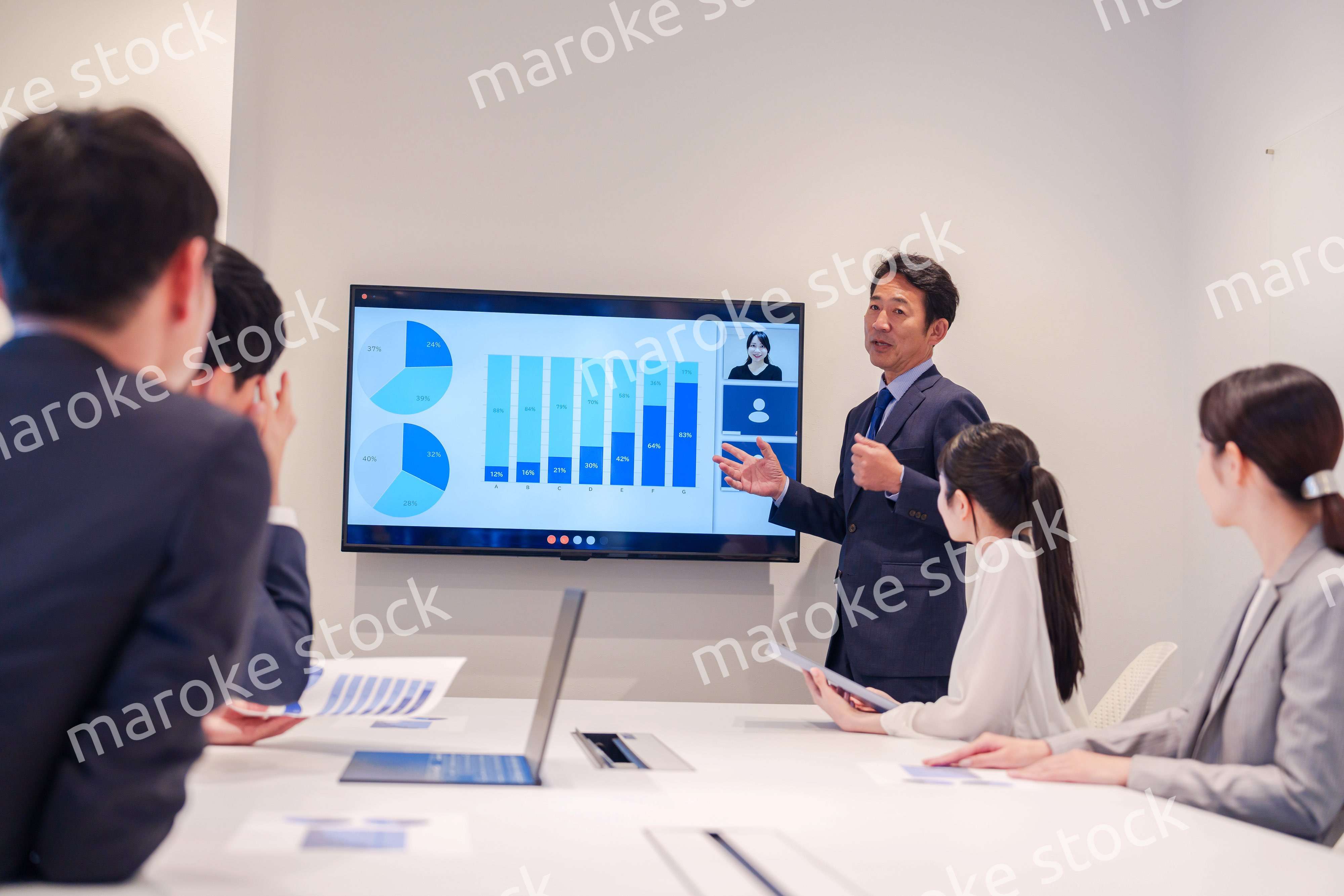 会議で資料を見ながらプレゼンをする中年のオフィスワーカー