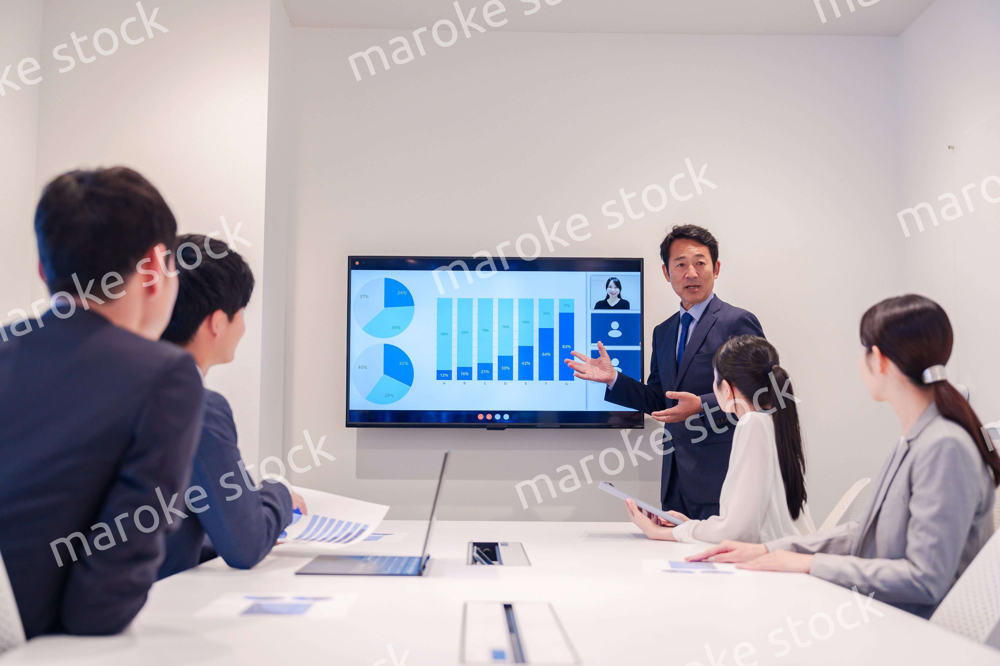 会議で資料を見ながらプレゼンをする中年のオフィスワーカー