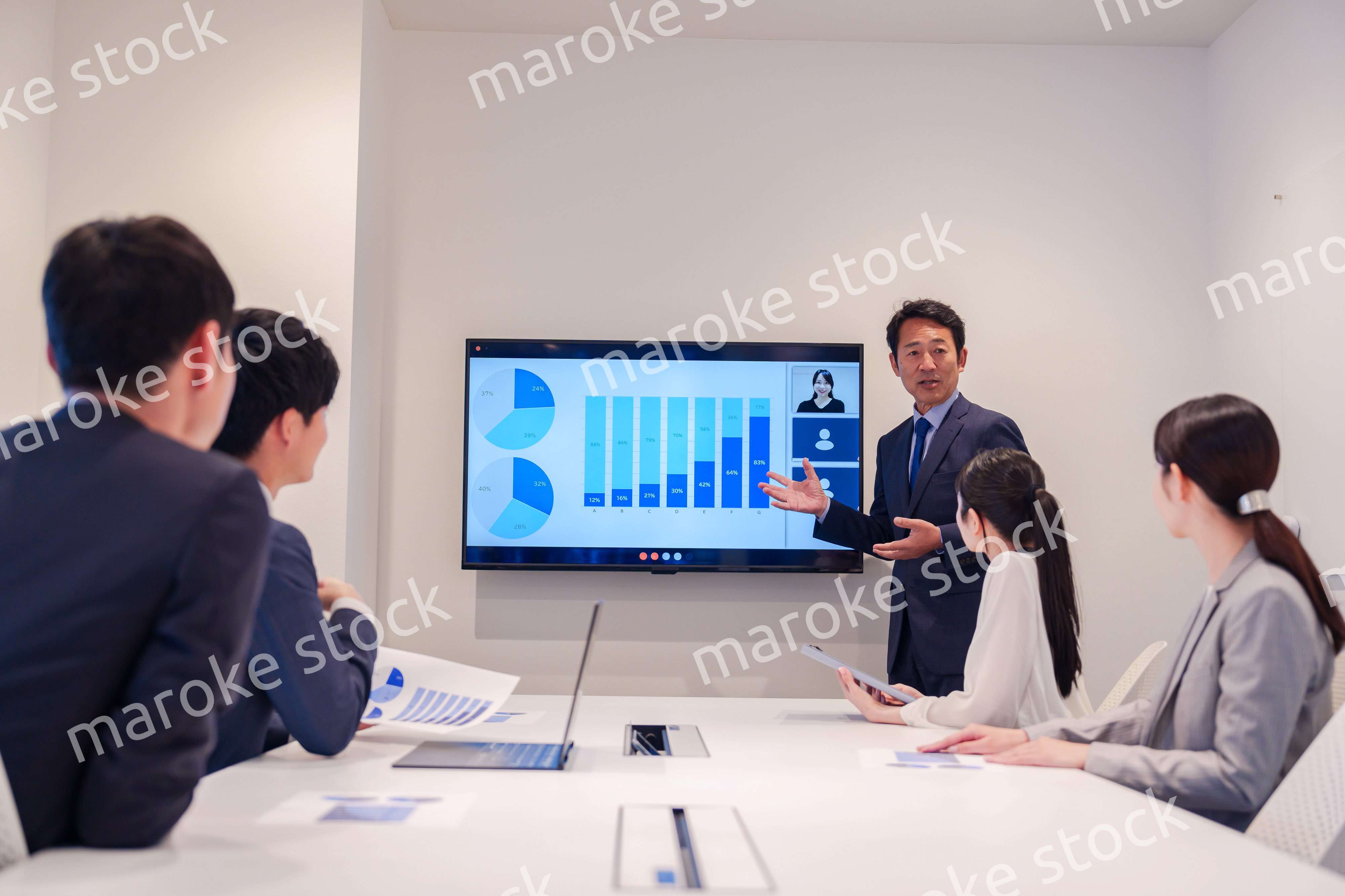 会議で資料を見ながらプレゼンをする中年のオフィスワーカー