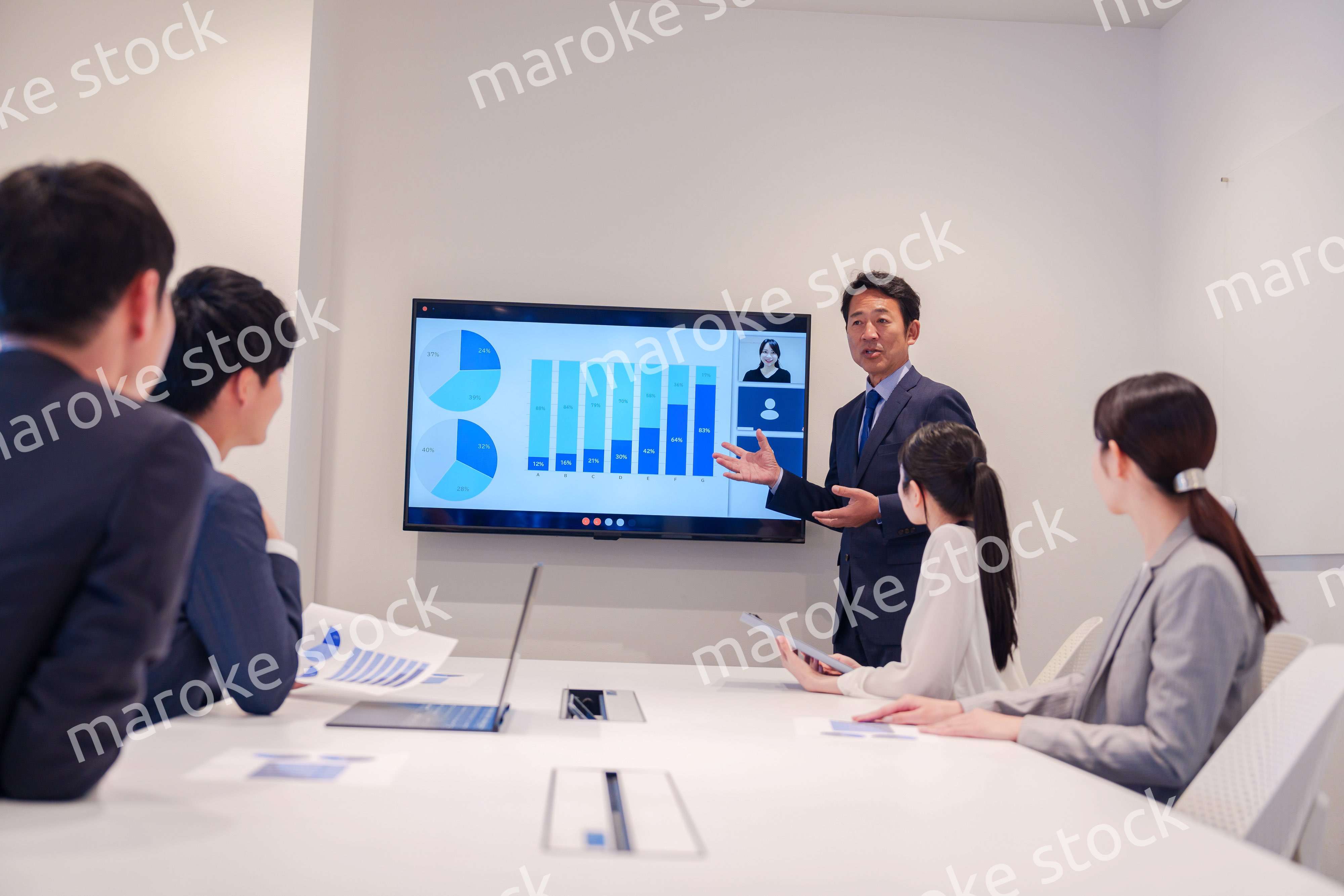 会議で資料を見ながらプレゼンをする中年のオフィスワーカー