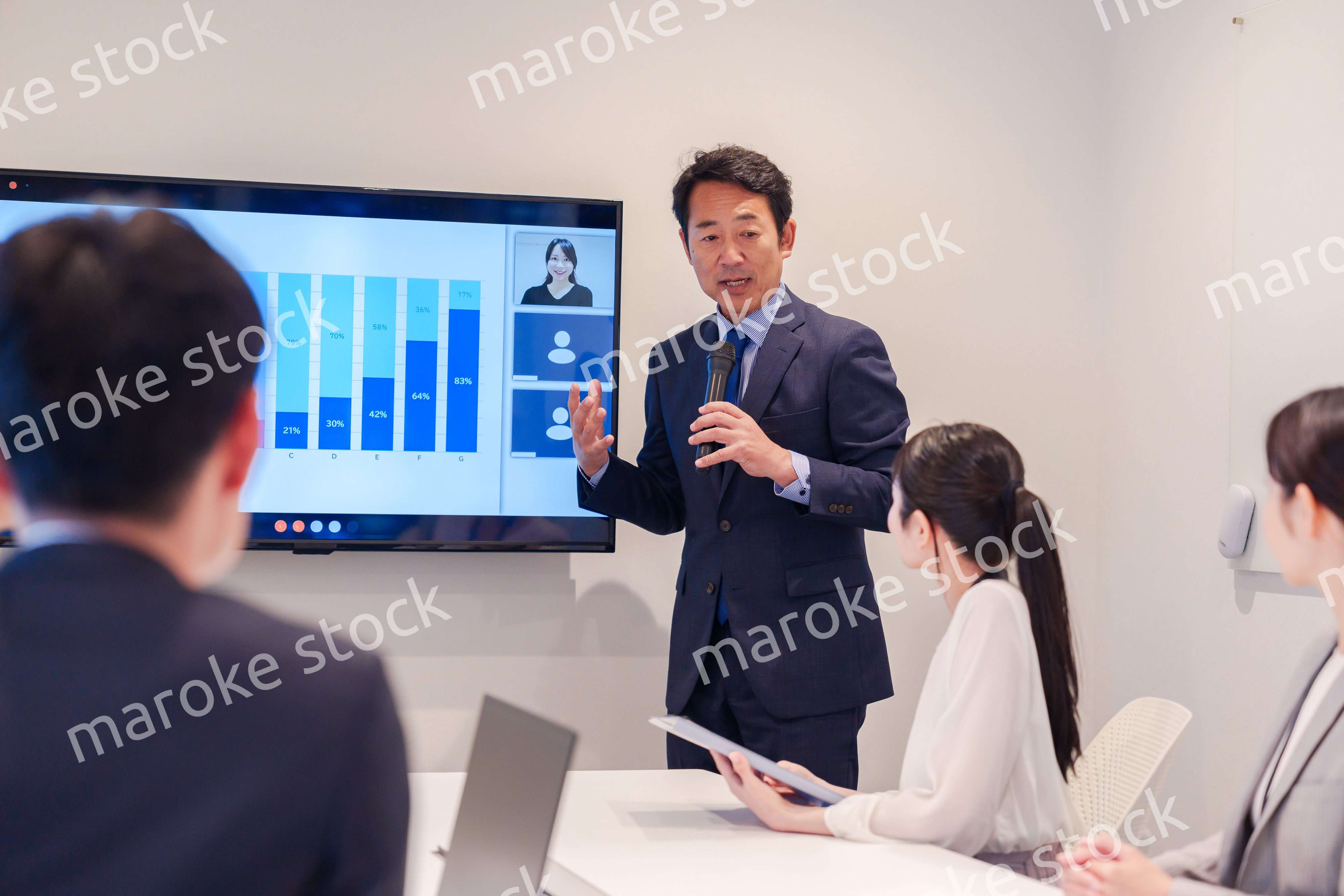 会議で資料を見ながらプレゼンをする中年のオフィスワーカー