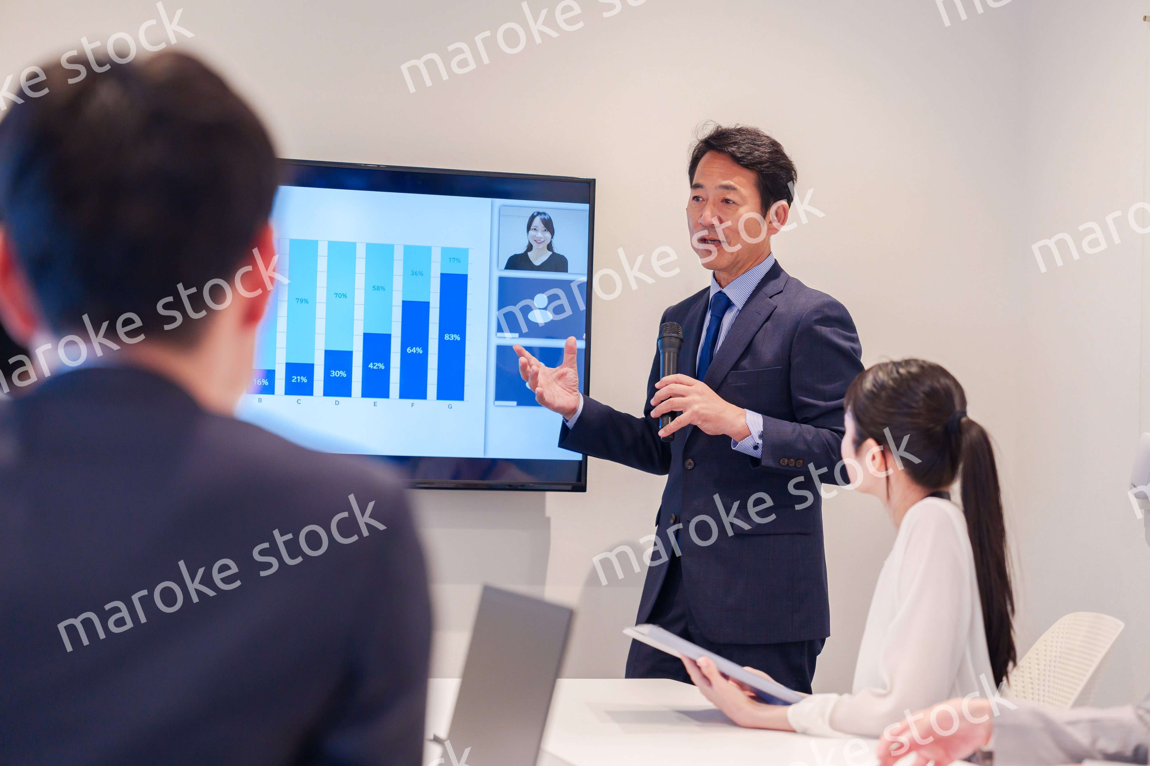 会議で資料を見ながらプレゼンをする中年のオフィスワーカー