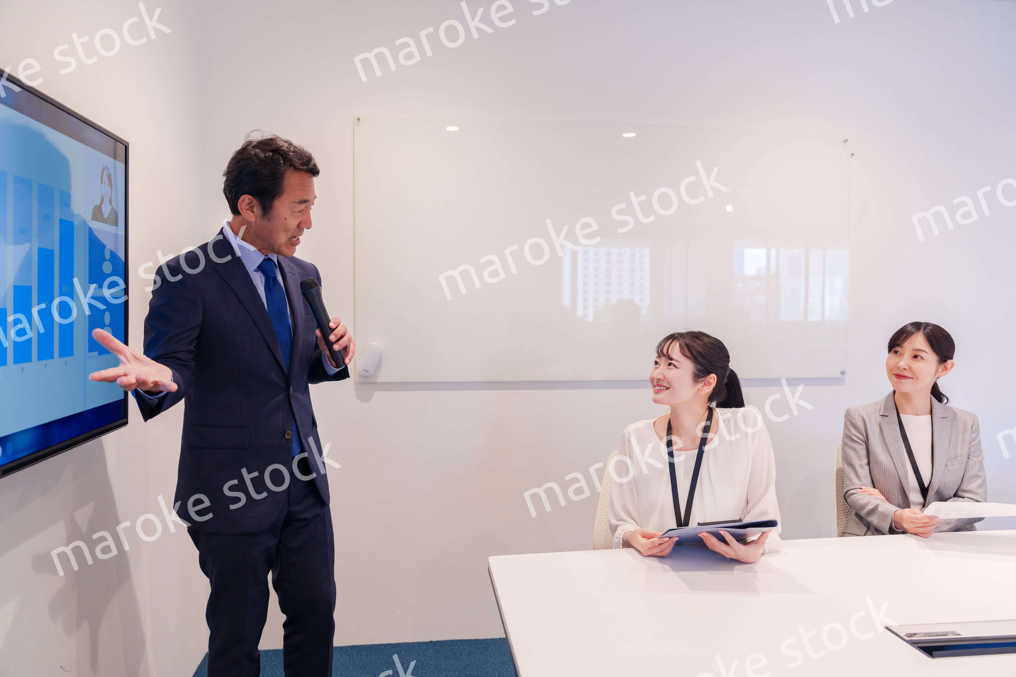 会議で資料を見ながらプレゼンをする中年のオフィスワーカー