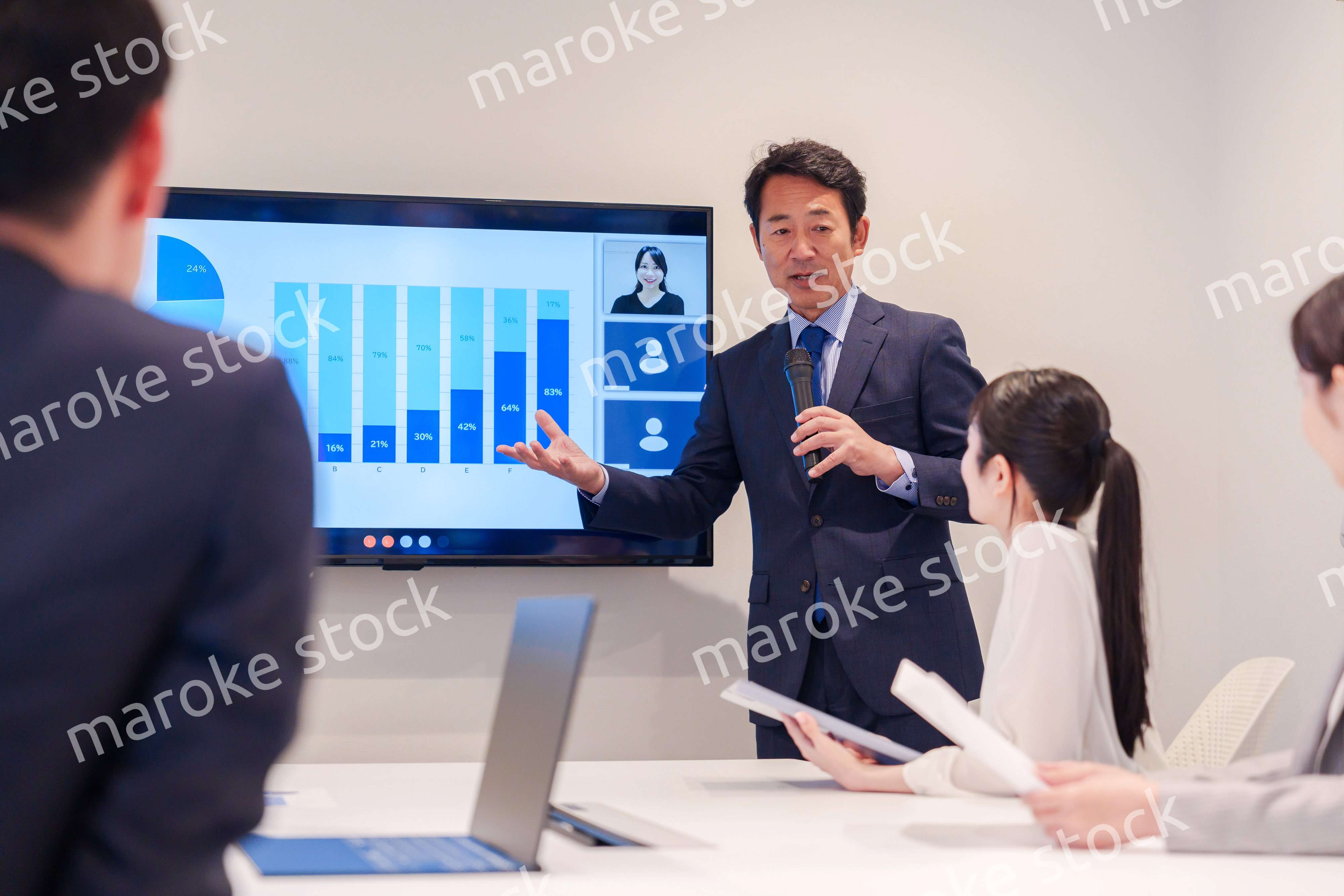 会議で資料を見ながらプレゼンをする中年のオフィスワーカー