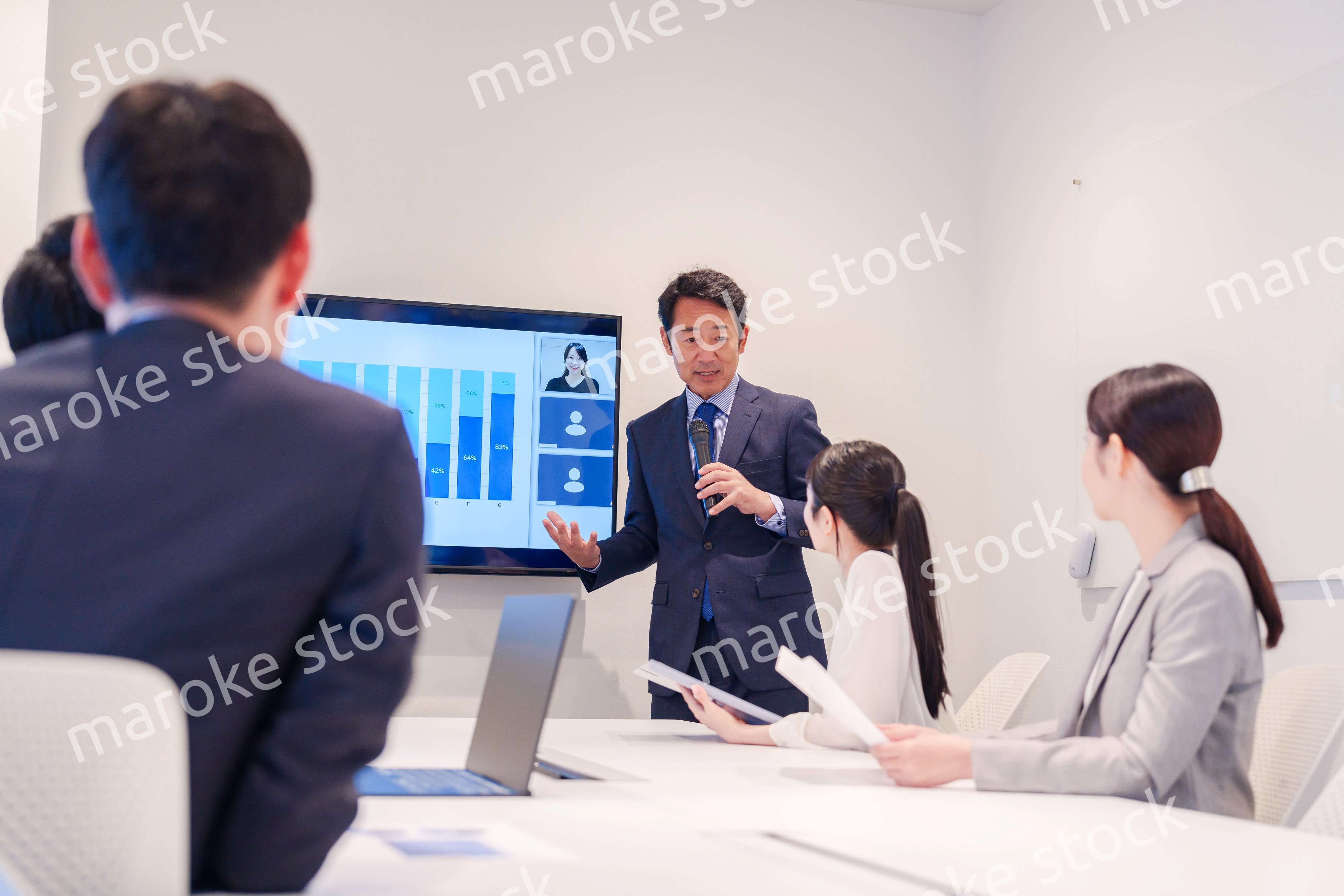 会議で資料を見ながらプレゼンをする中年のオフィスワーカー