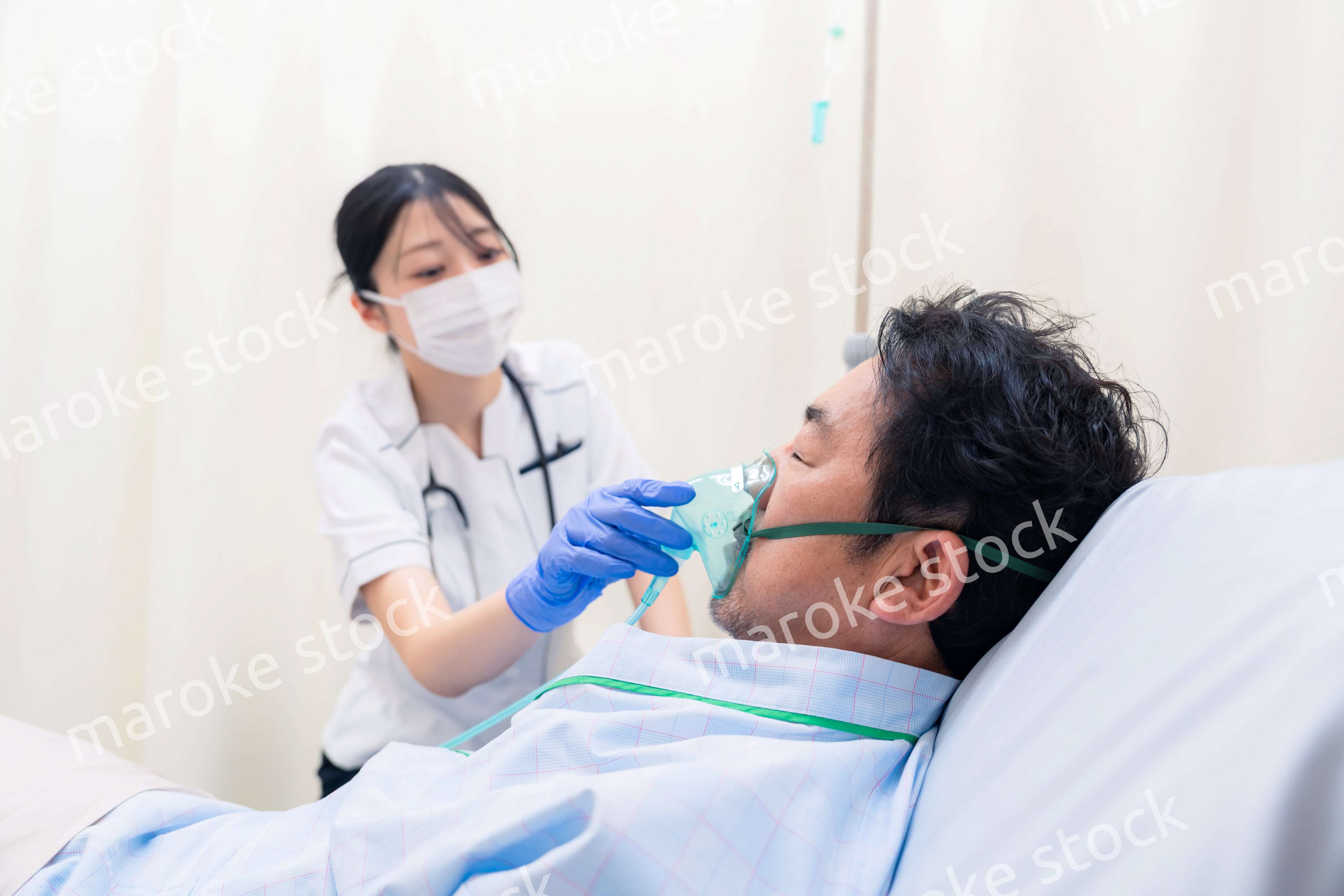 人工呼吸器をつけた患者のケアをする看護師の女性