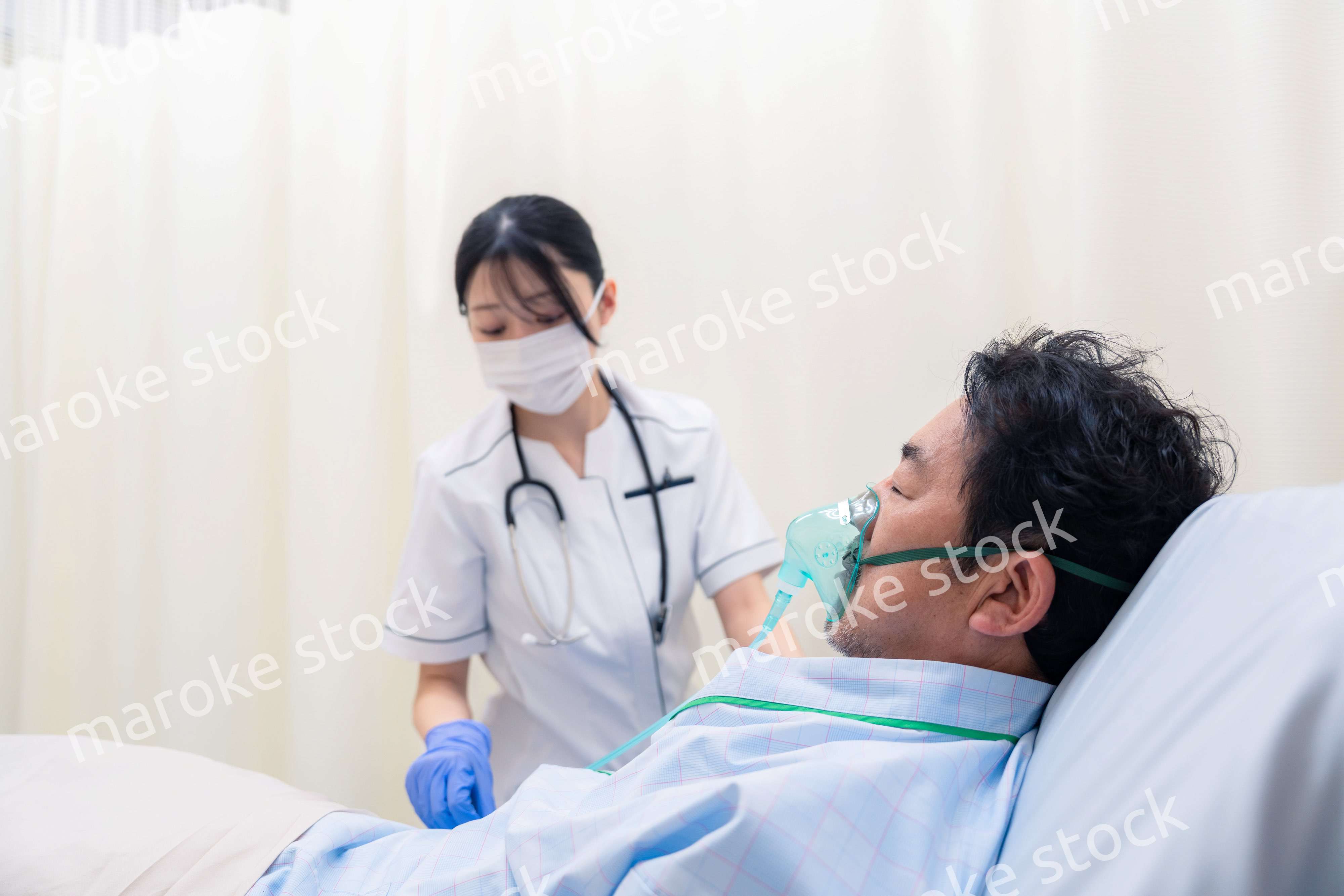 人工呼吸器をつけた患者のケアをする看護師の女性