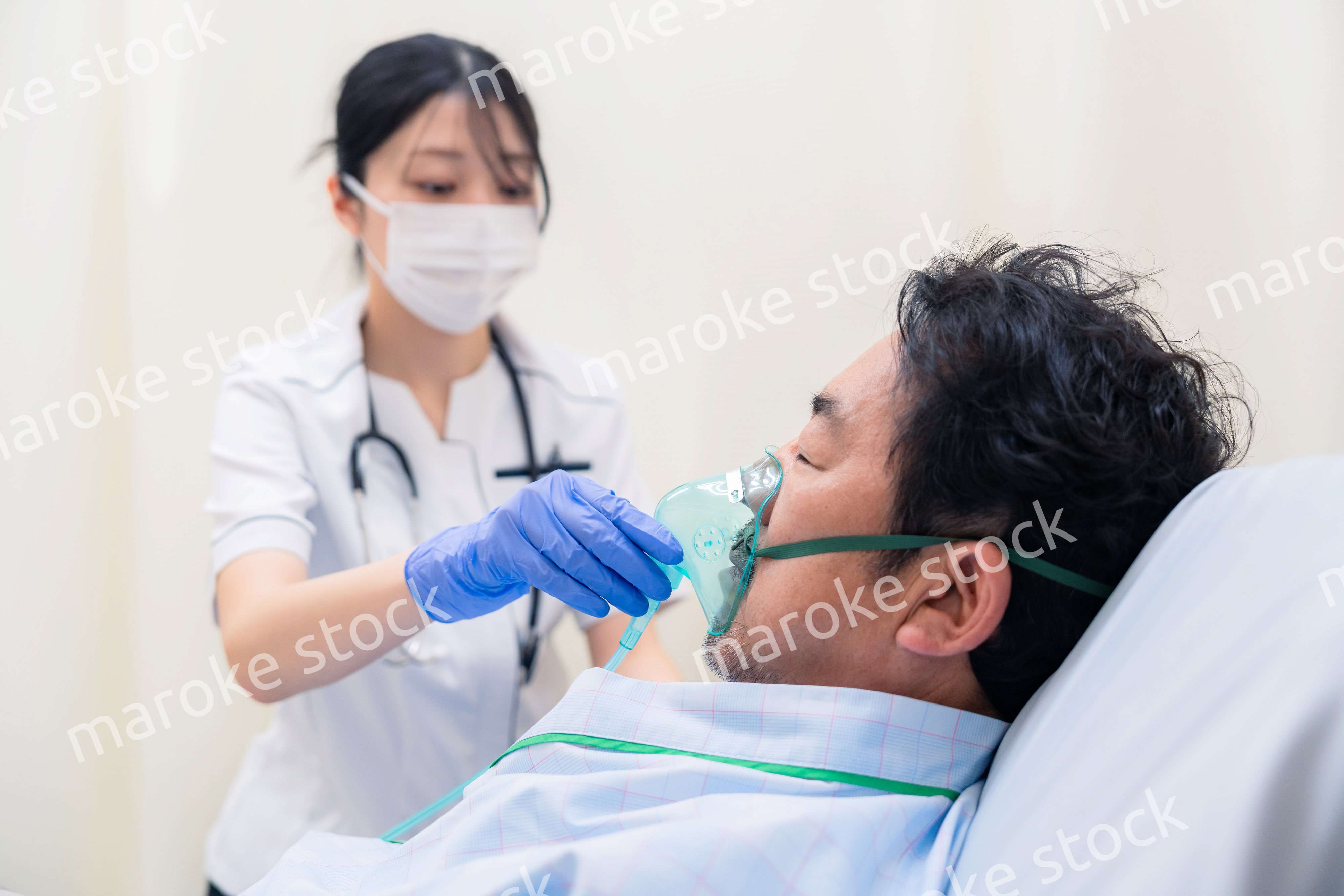 人工呼吸器をつけた患者のケアをする看護師の女性