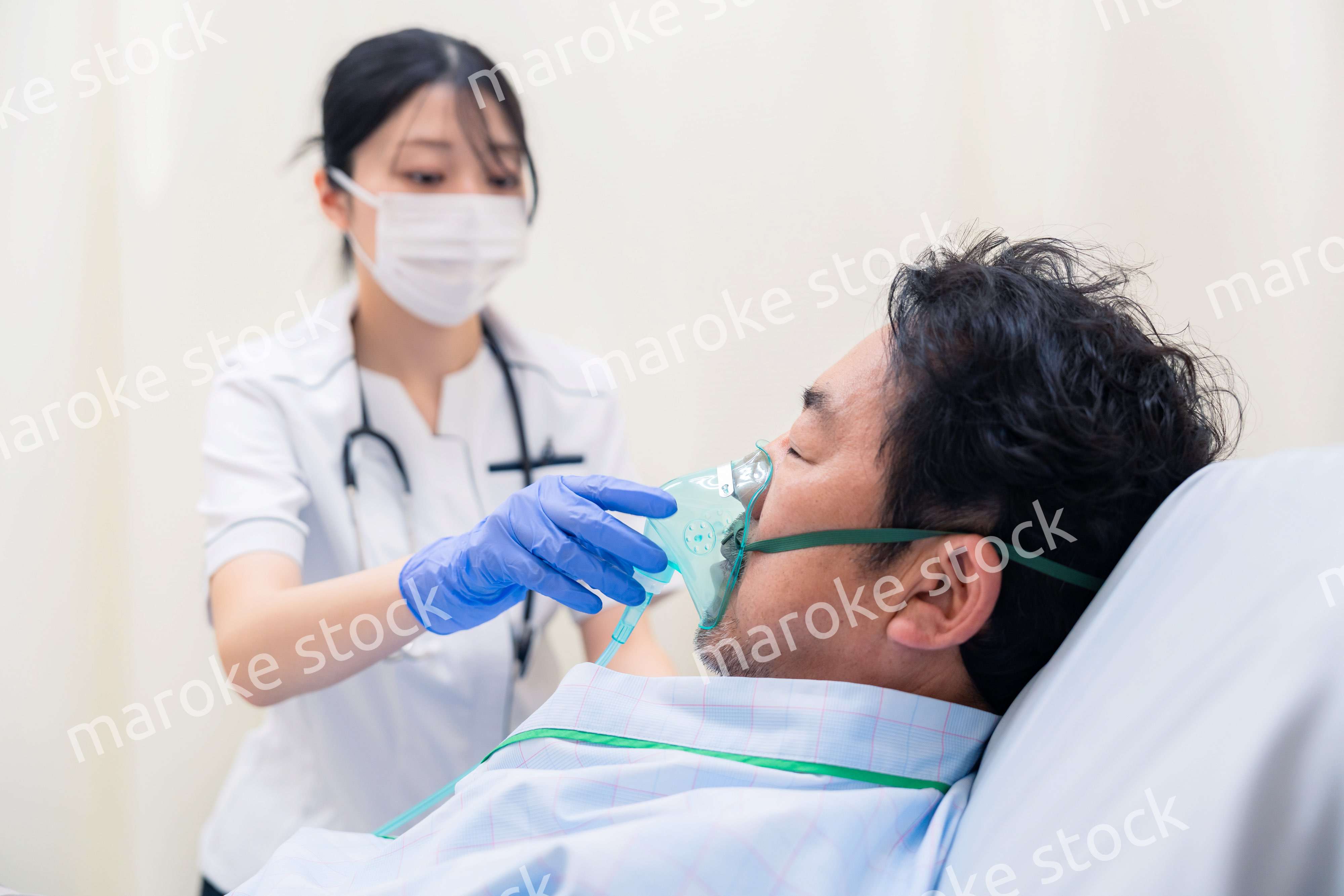 人工呼吸器をつけた患者のケアをする看護師の女性