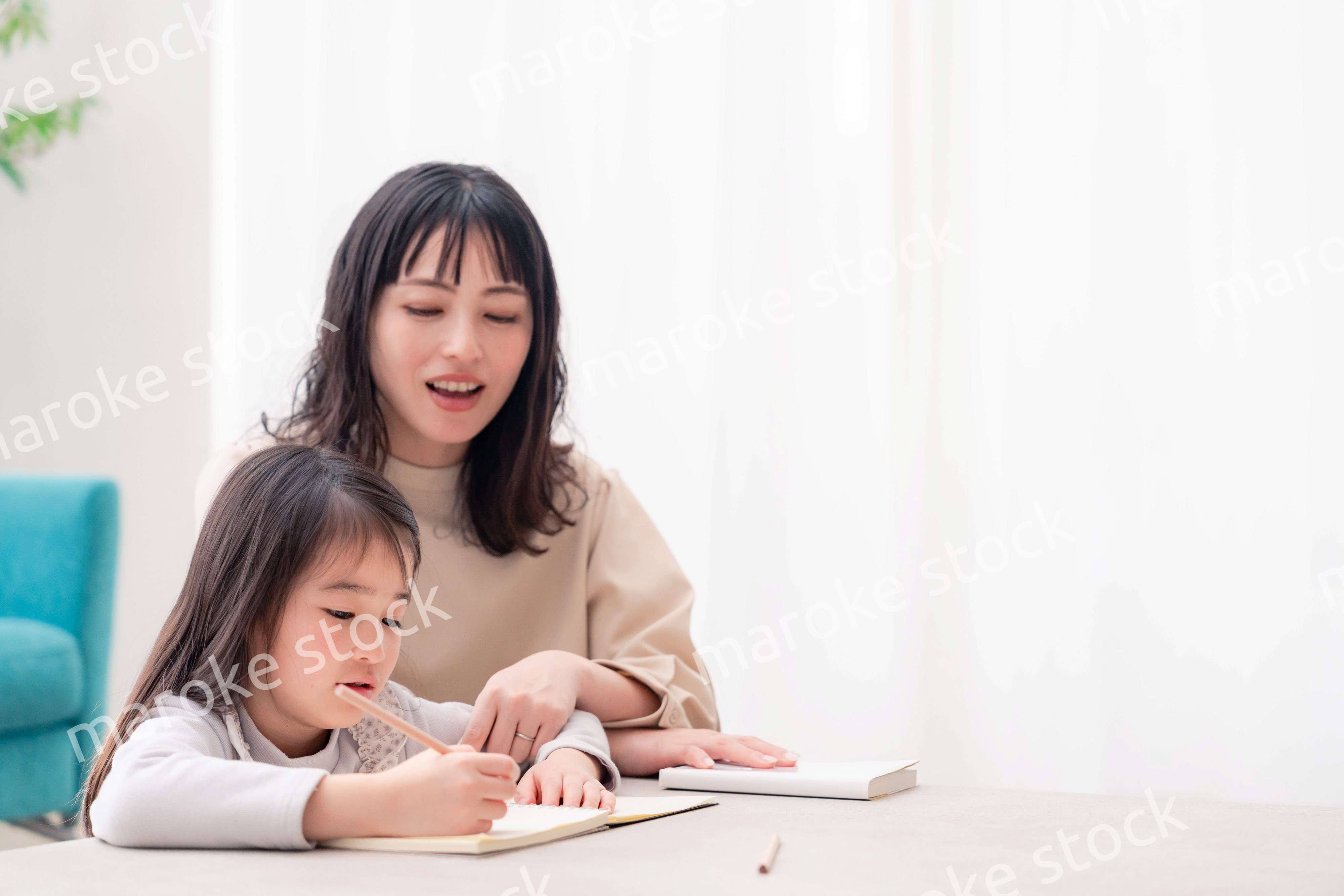 幼稚園児の女の子と一緒に勉強をするお母さん