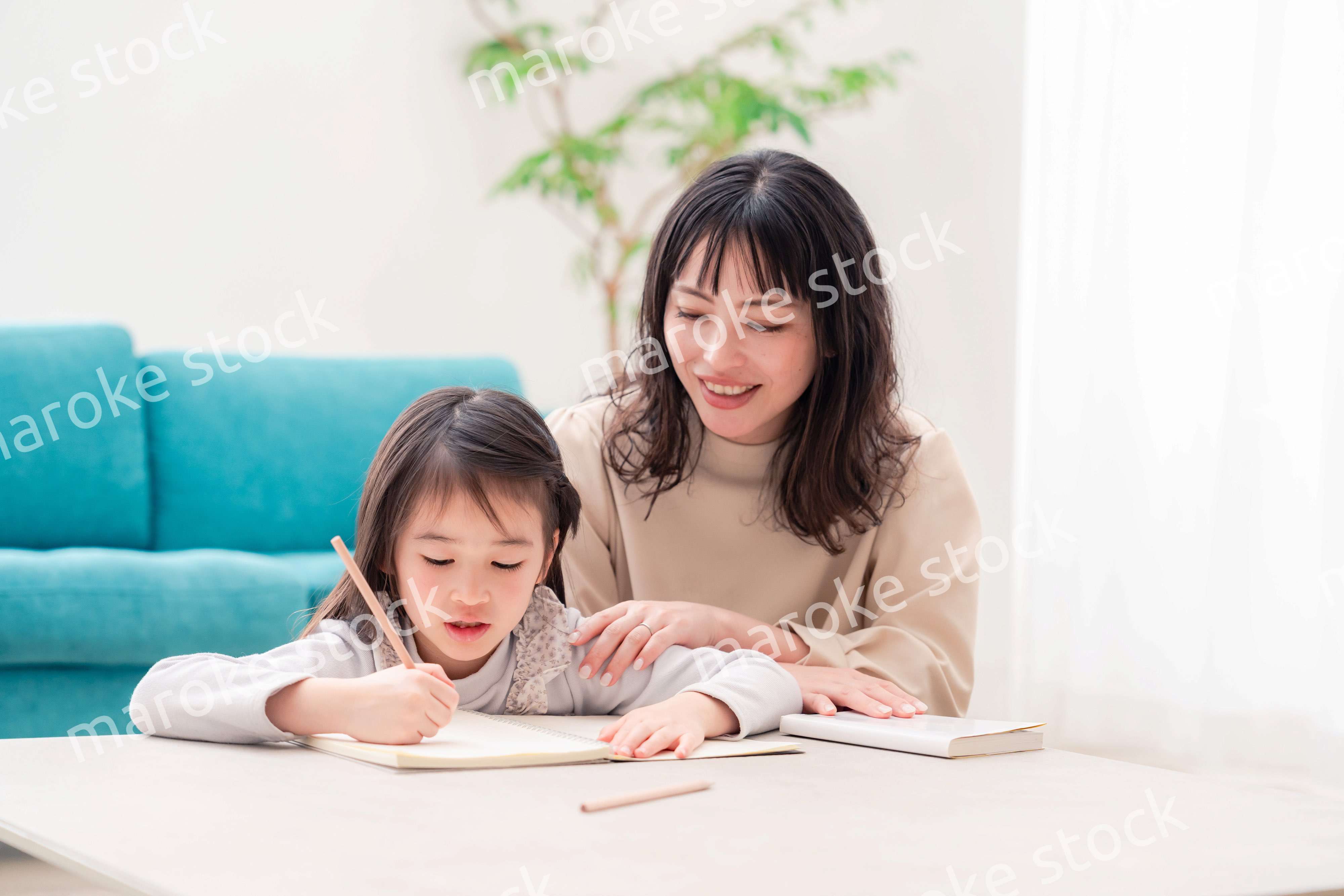 幼稚園児の女の子と一緒に勉強をするお母さん