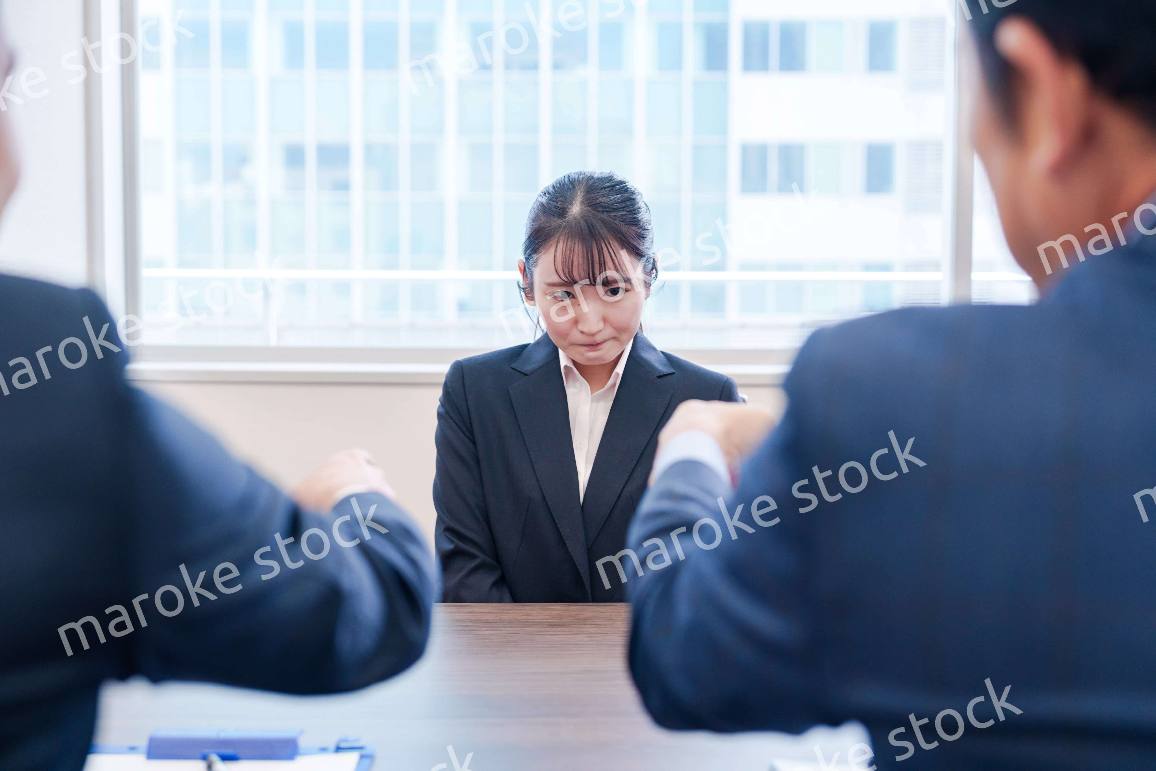 オフィスで上司に詰められて悲しい表情をする女性社員