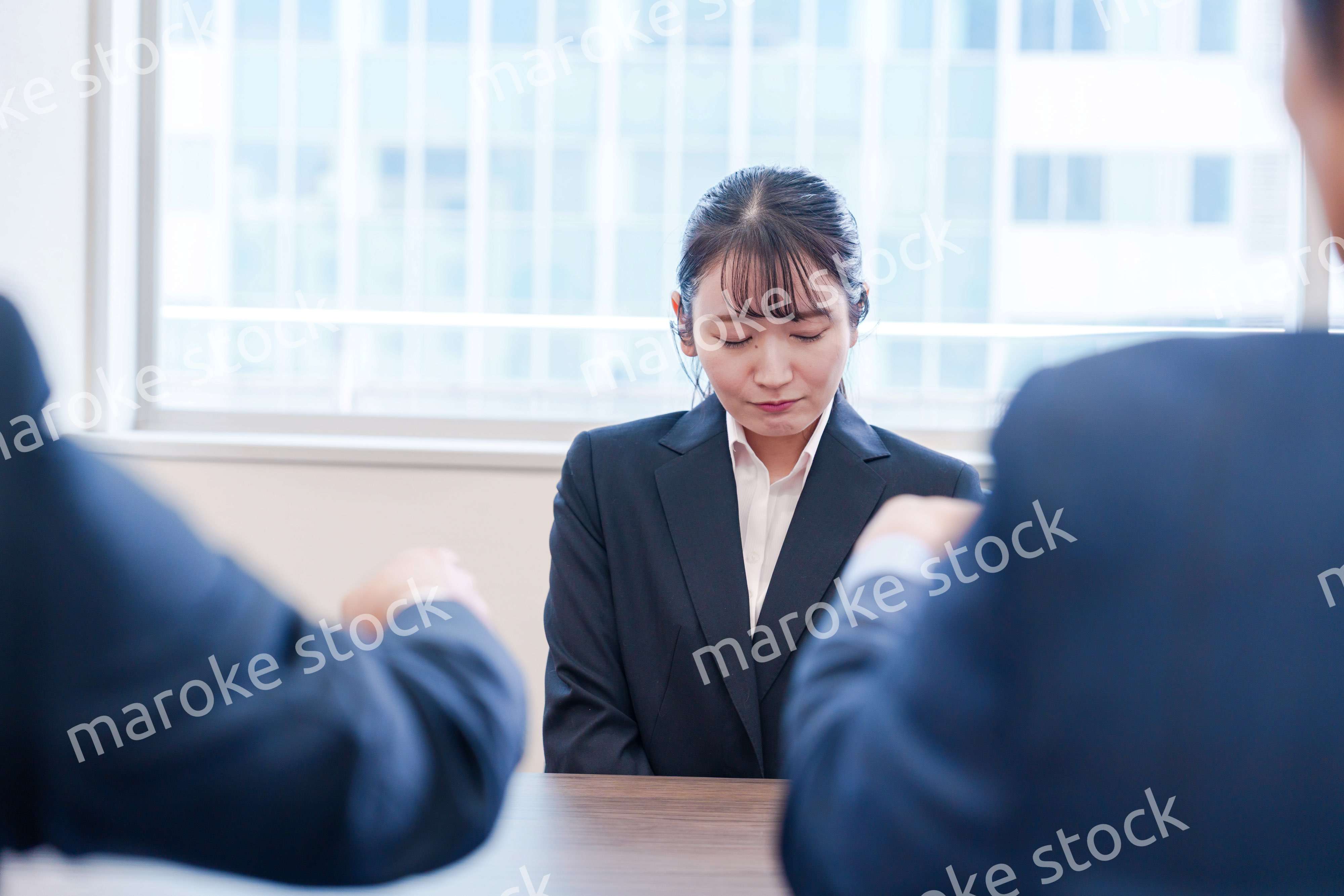 オフィスで上司に詰められて悲しい表情をする女性社員