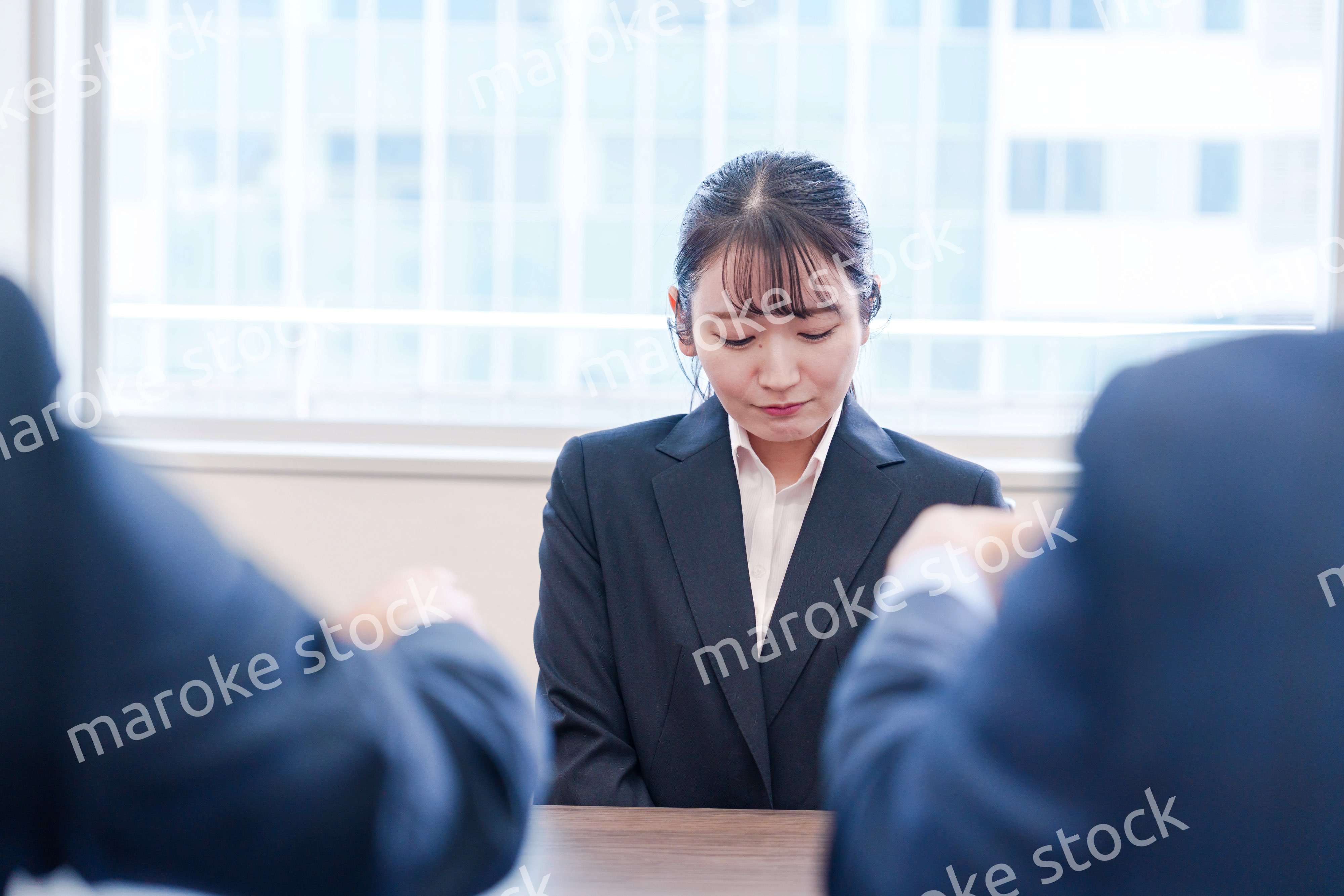 オフィスで上司に詰められて悲しい表情をする女性社員