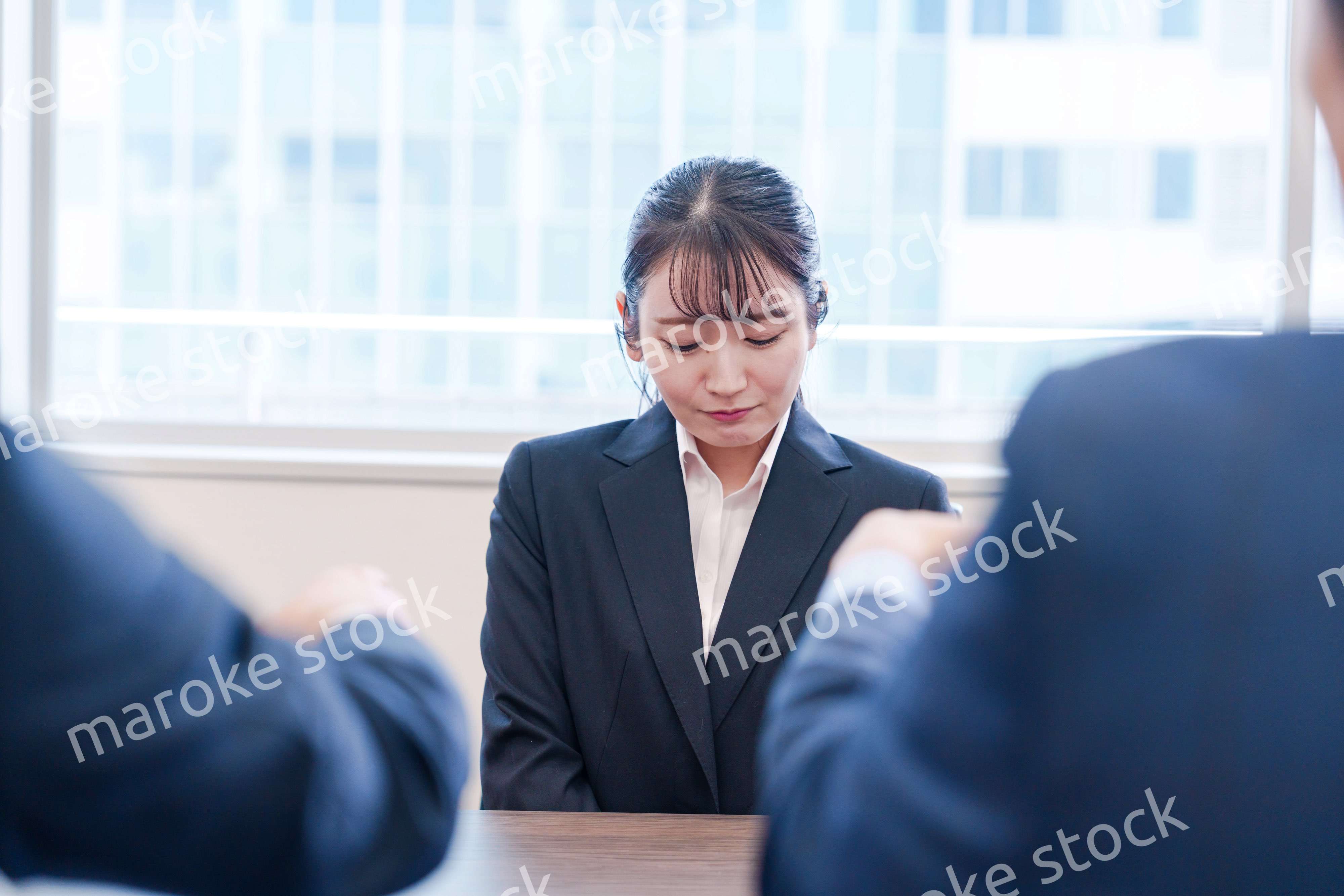 オフィスで上司に詰められて悲しい表情をする女性社員