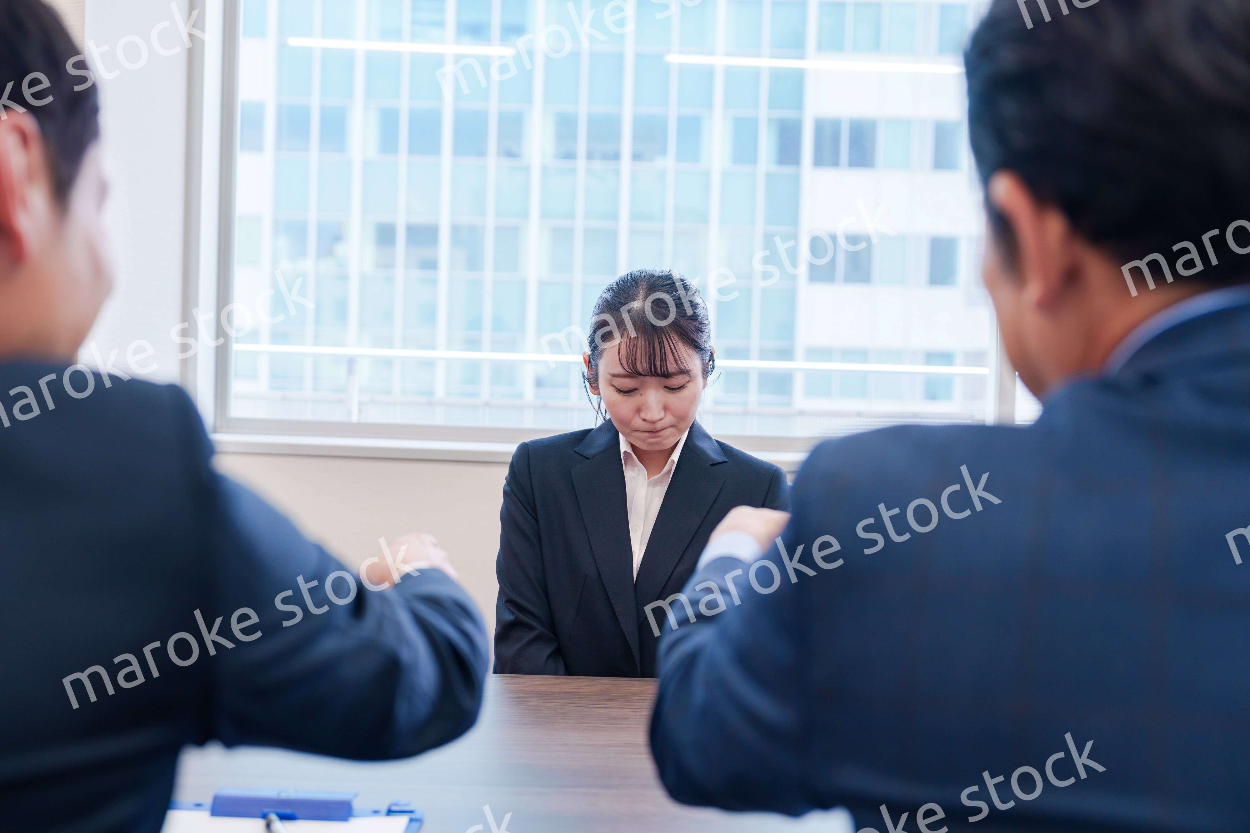 オフィスで上司に詰められて悲しい表情をする女性社員