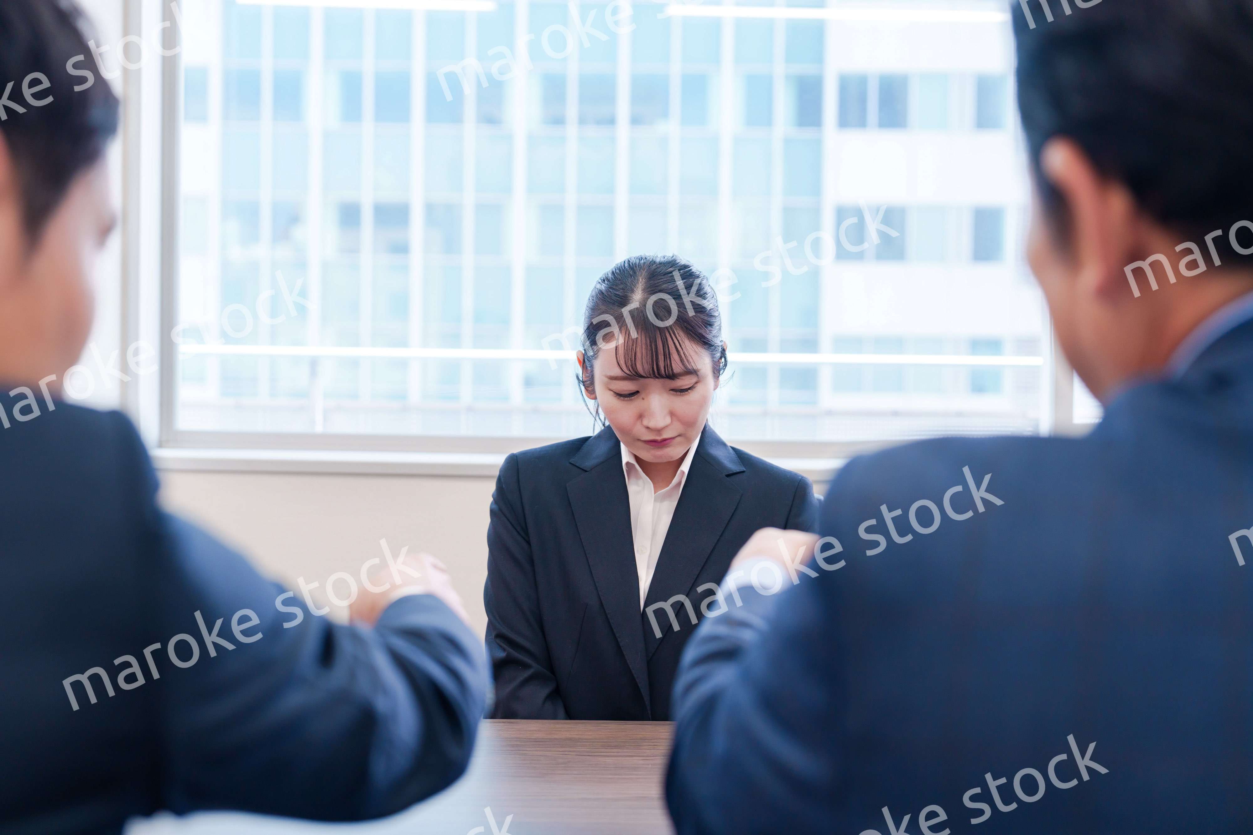 オフィスで上司に詰められて悲しい表情をする女性社員