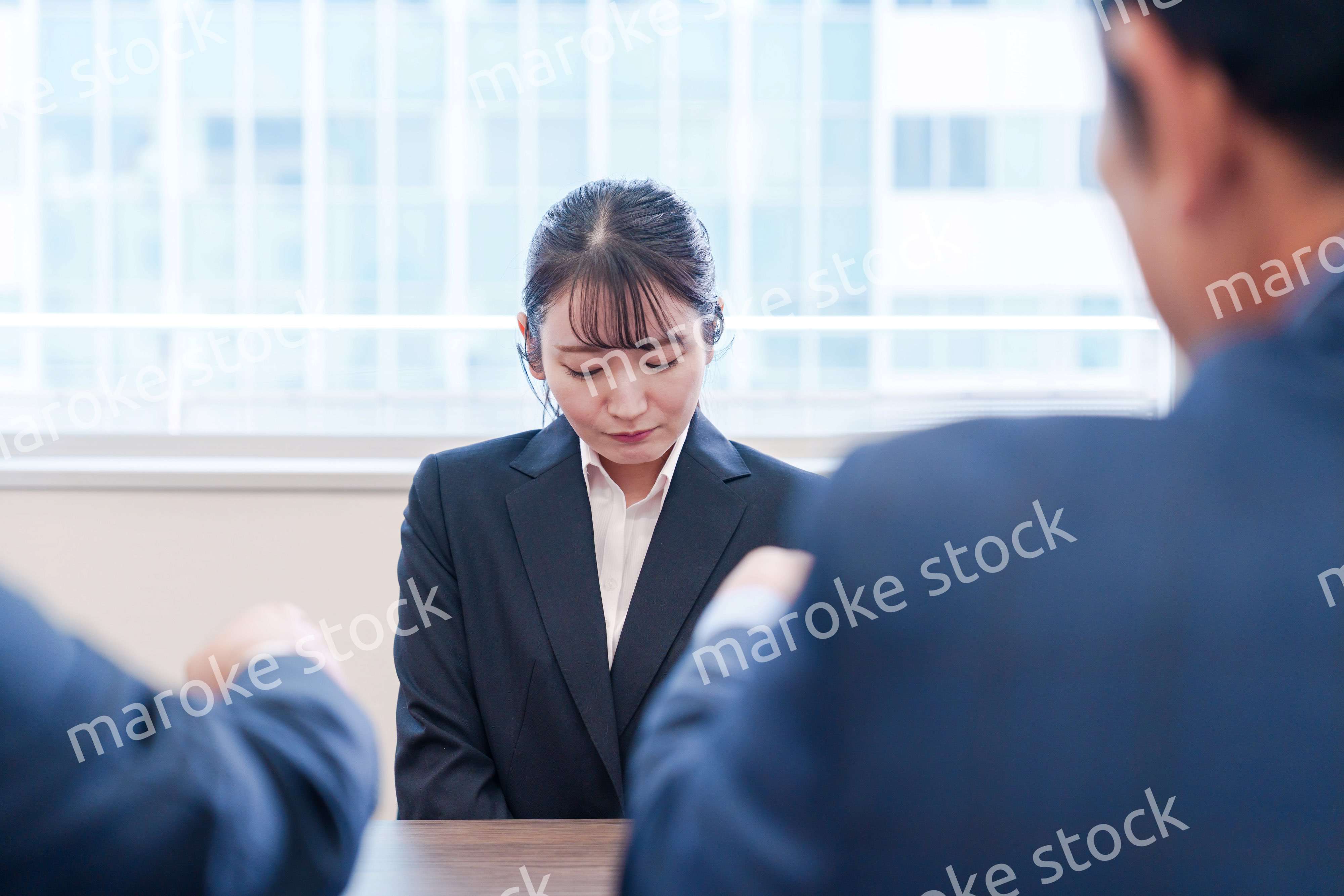 オフィスで上司に詰められて悲しい表情をする女性社員