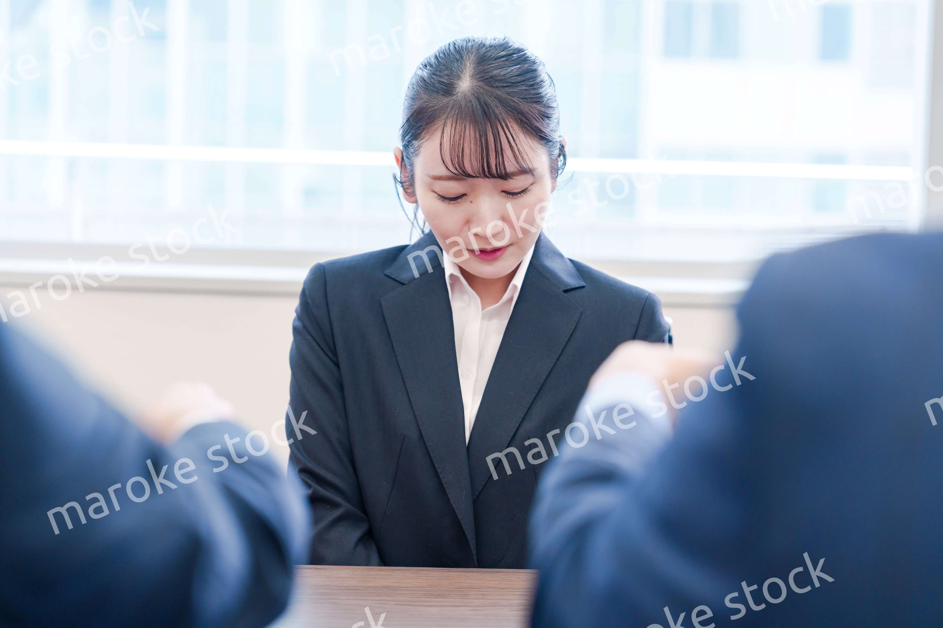 オフィスで上司に詰められて悲しい表情をする女性社員