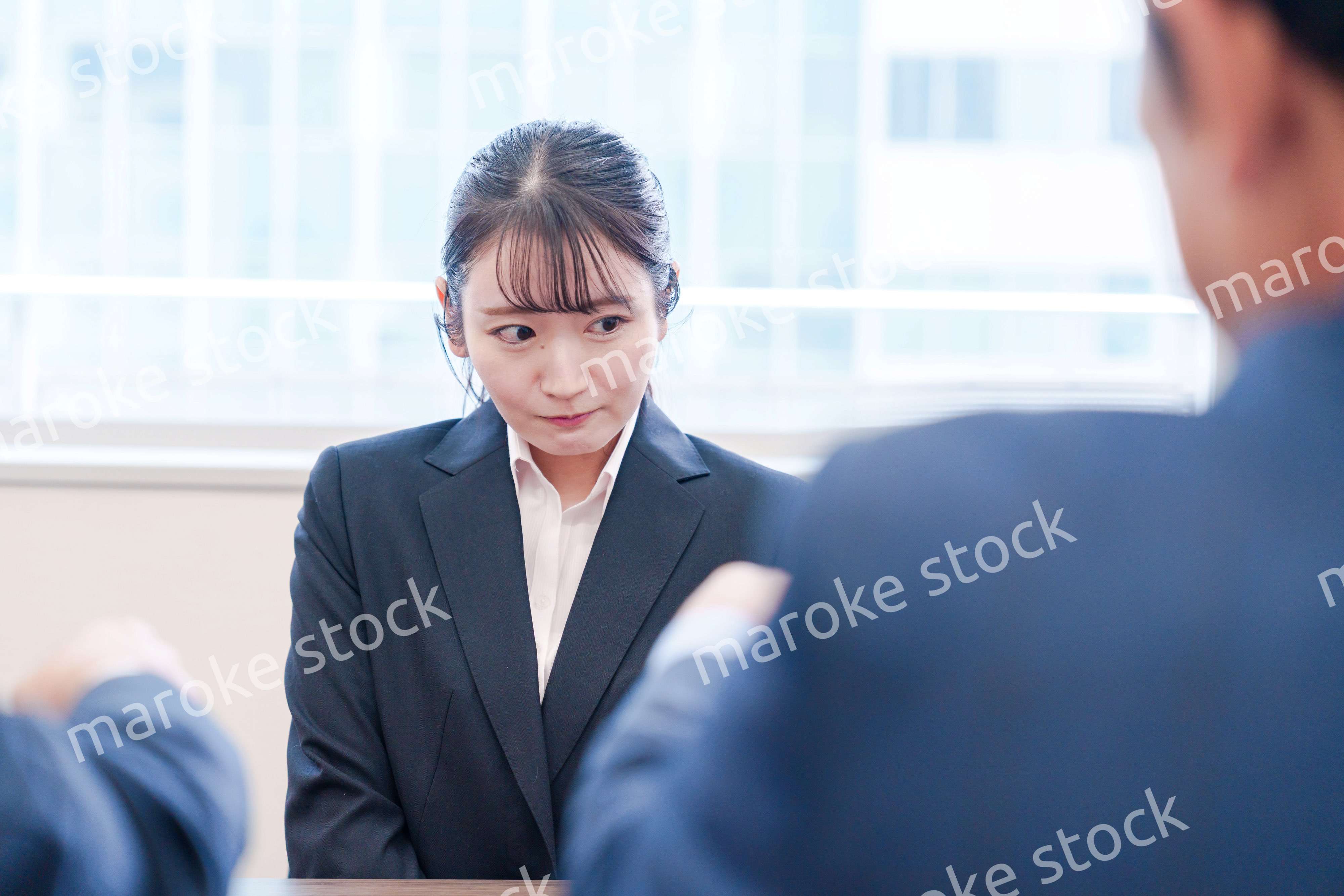 オフィスで上司に詰められて悲しい表情をする女性社員