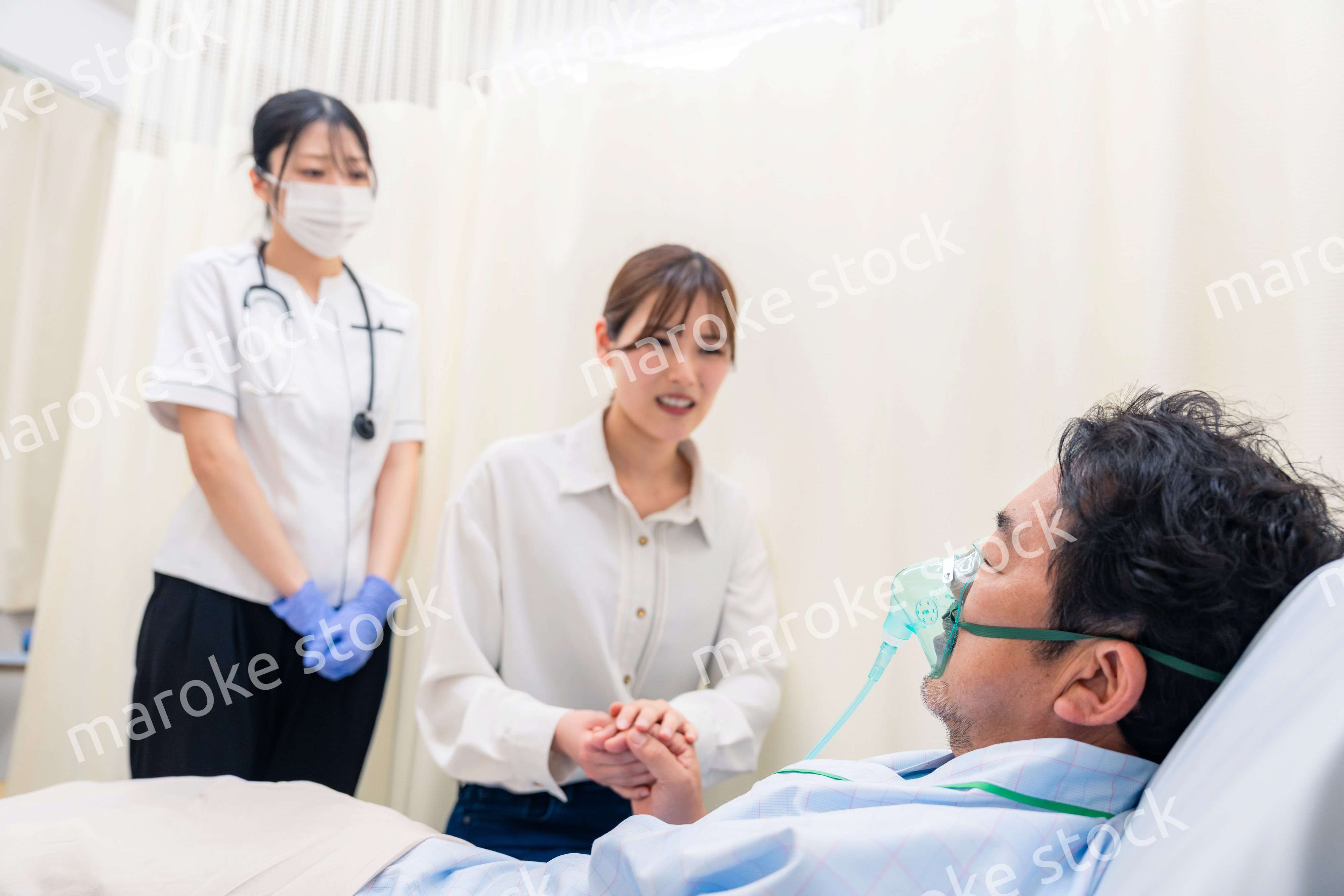 人工呼吸器をつけた家族のお見舞いをする若い女性