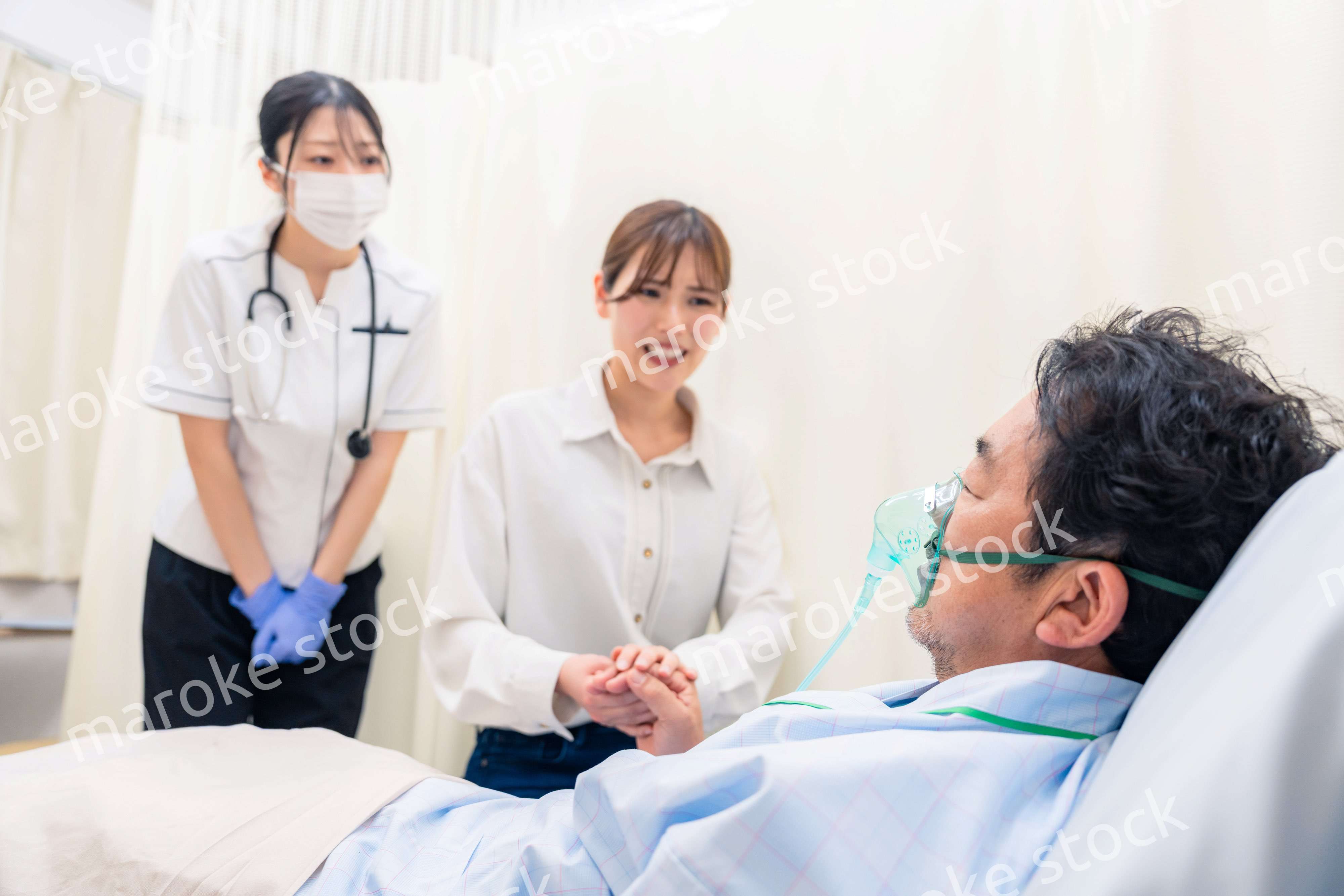 人工呼吸器をつけた家族のお見舞いをする若い女性