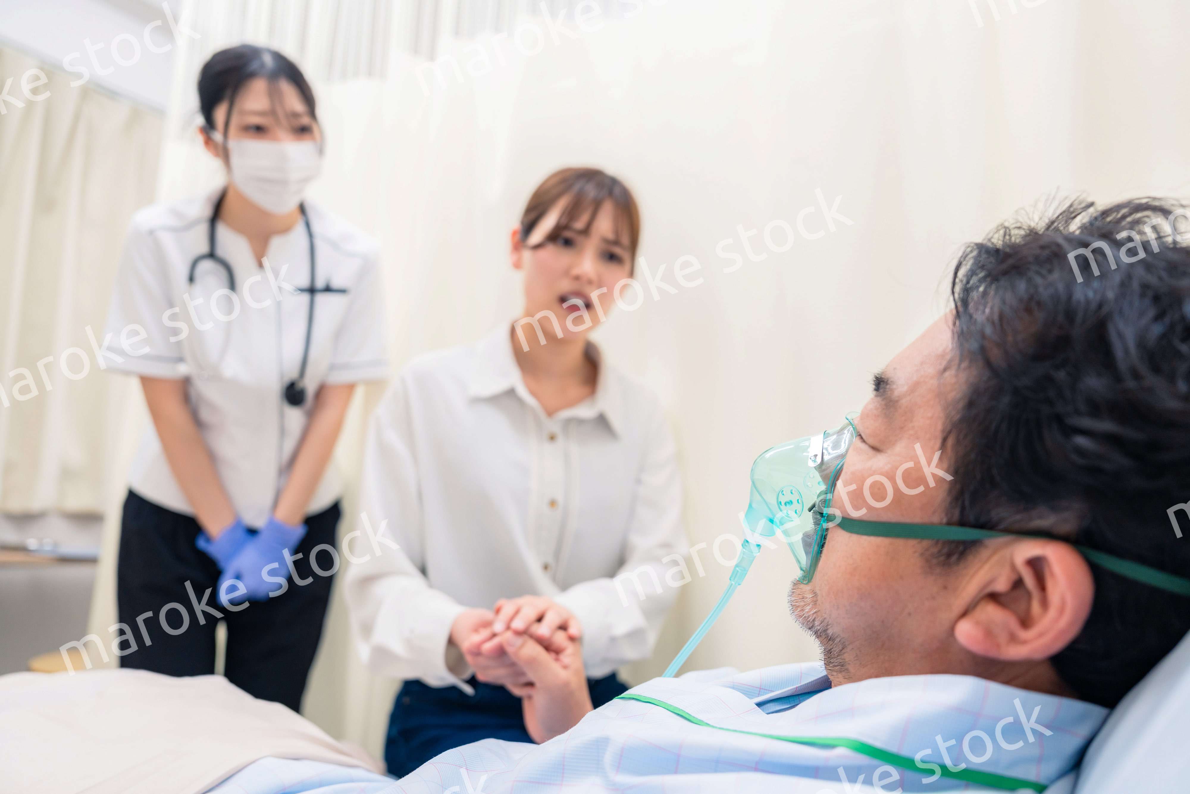 人工呼吸器をつけた家族のお見舞いをする若い女性