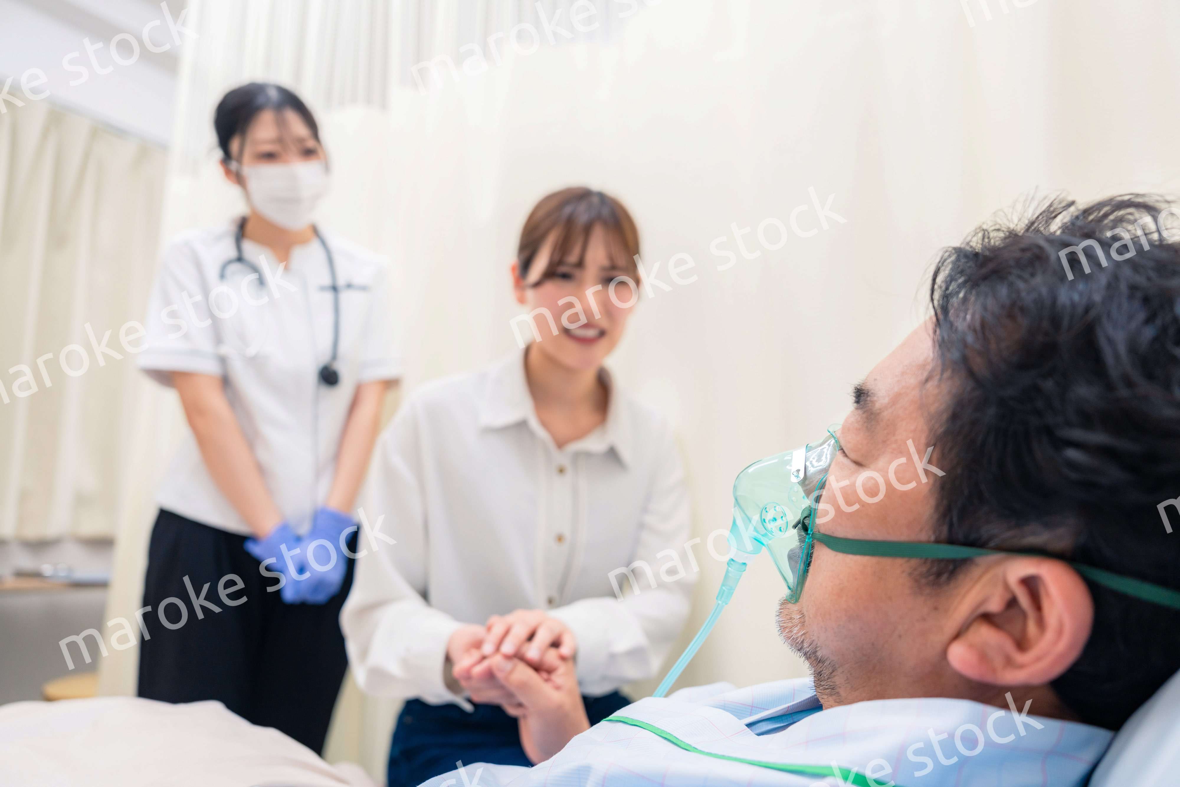 人工呼吸器をつけた家族のお見舞いをする若い女性