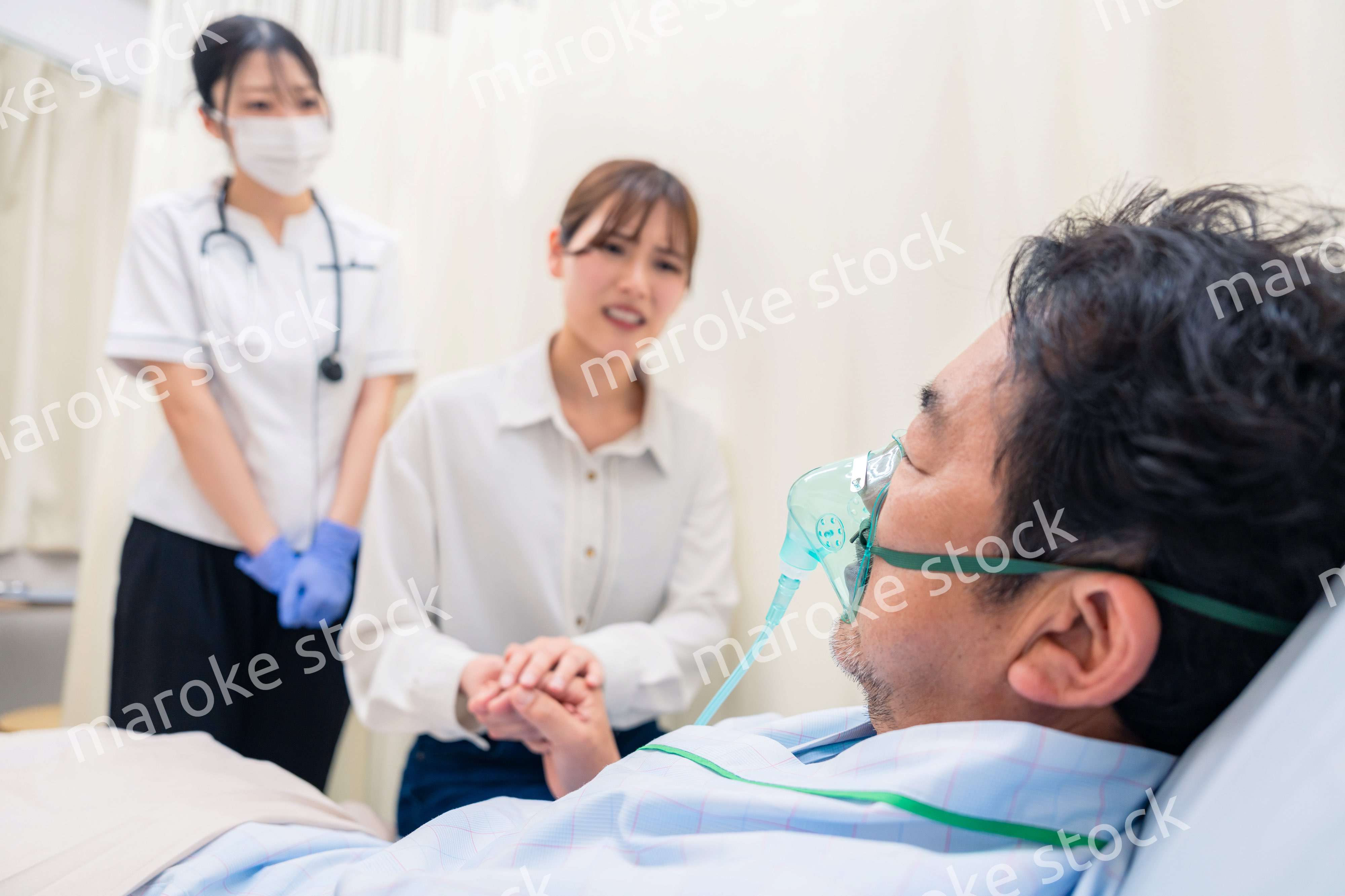 人工呼吸器をつけた家族のお見舞いをする若い女性