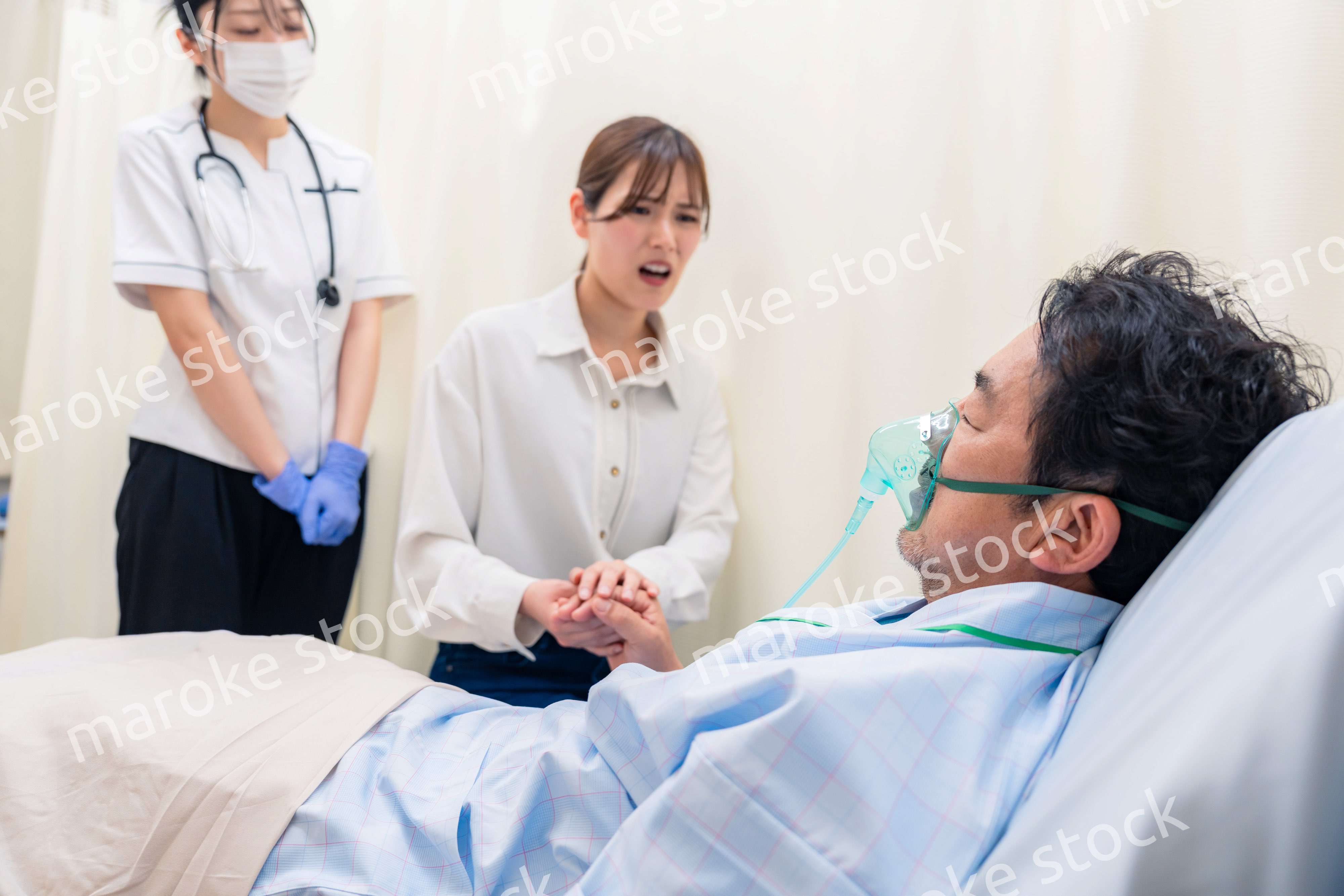 人工呼吸器をつけた家族のお見舞いをする若い女性