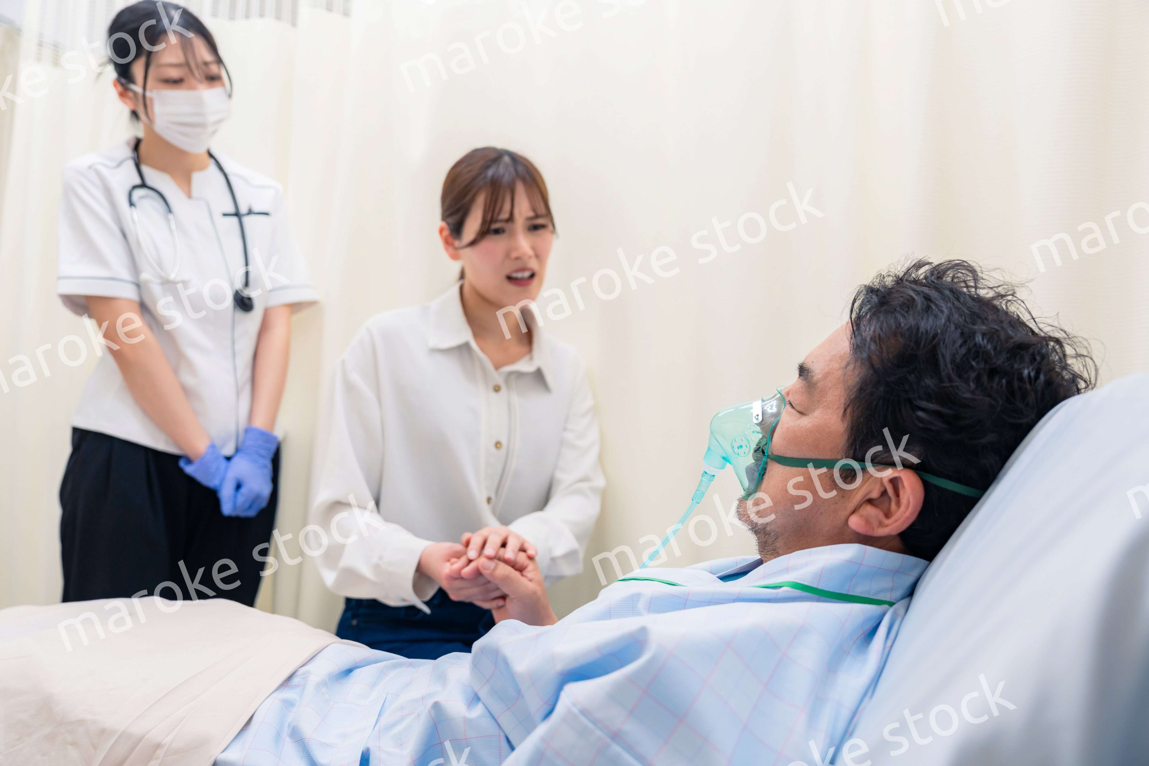 人工呼吸器をつけた家族のお見舞いをする若い女性