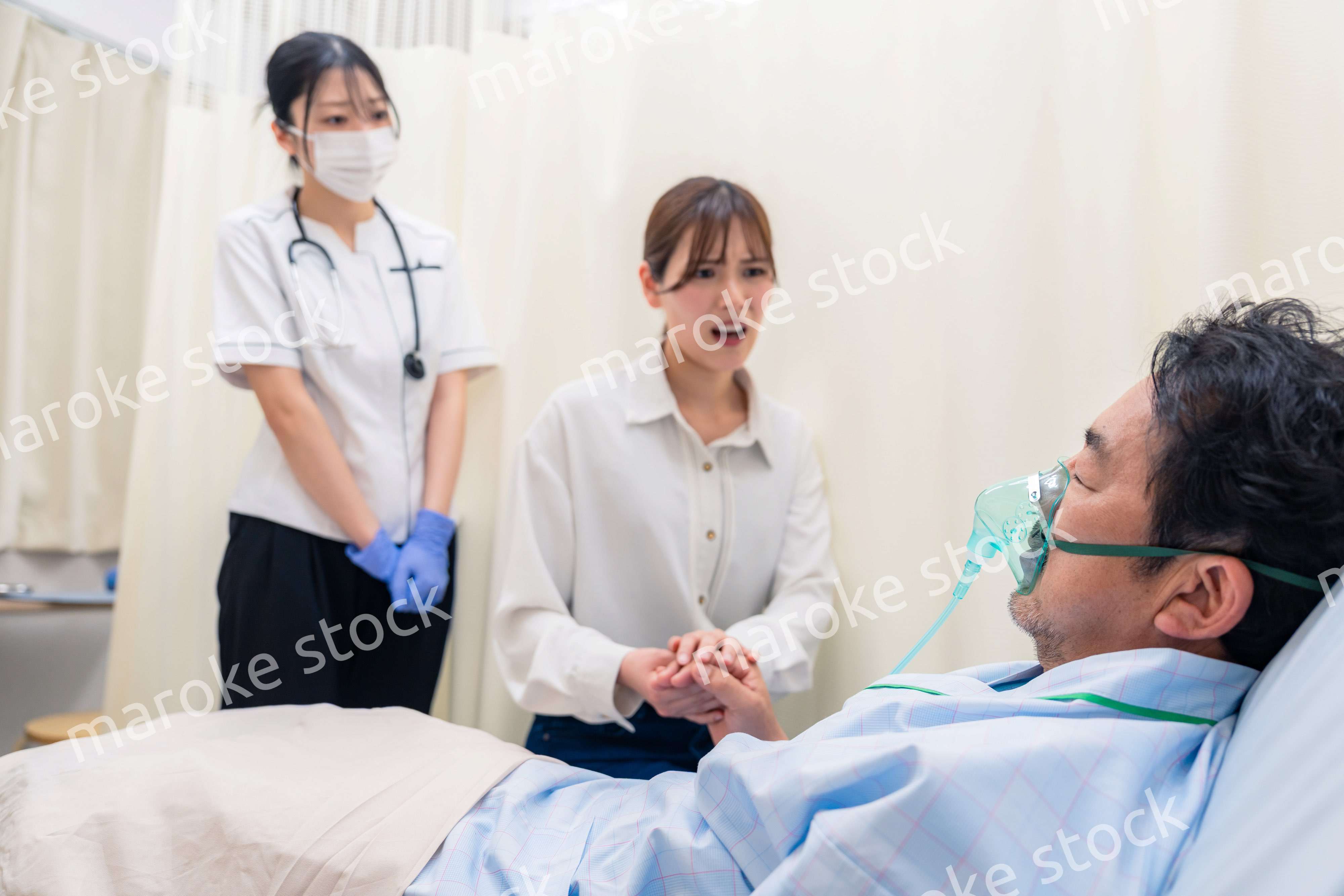 人工呼吸器をつけた家族のお見舞いをする若い女性