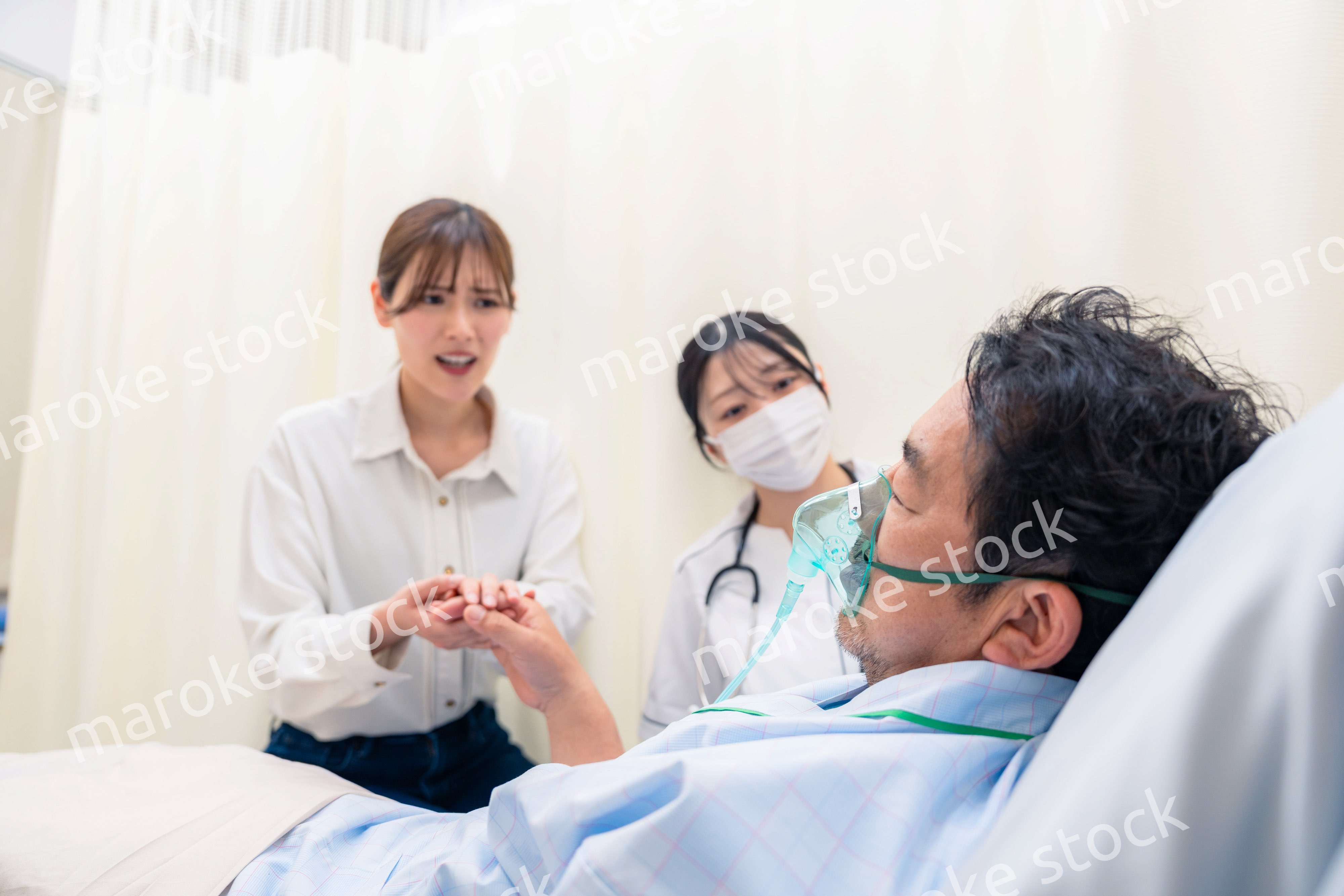 人工呼吸器をつけた家族のお見舞いをする若い女性