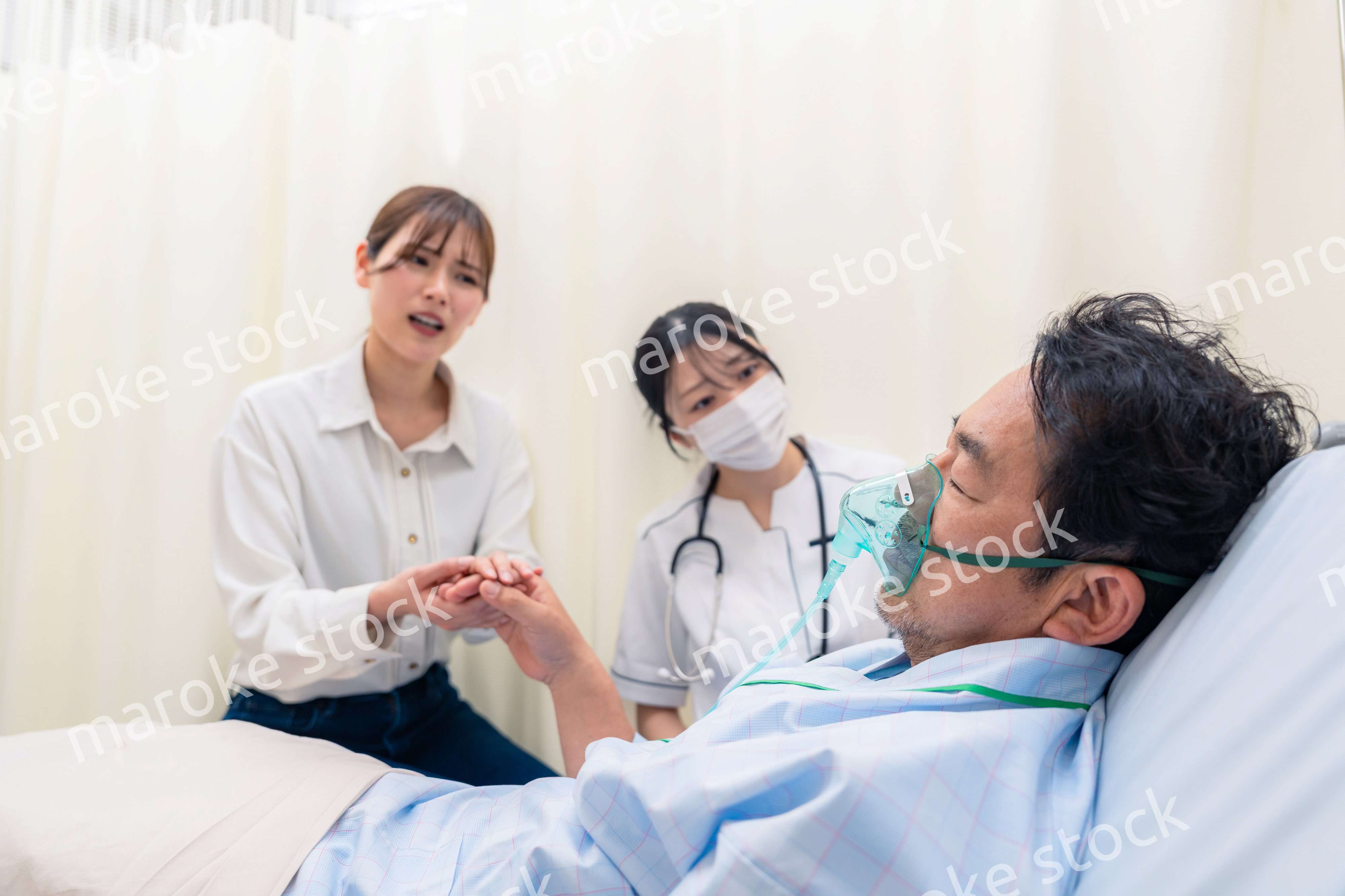 人工呼吸器をつけた家族のお見舞いをする若い女性