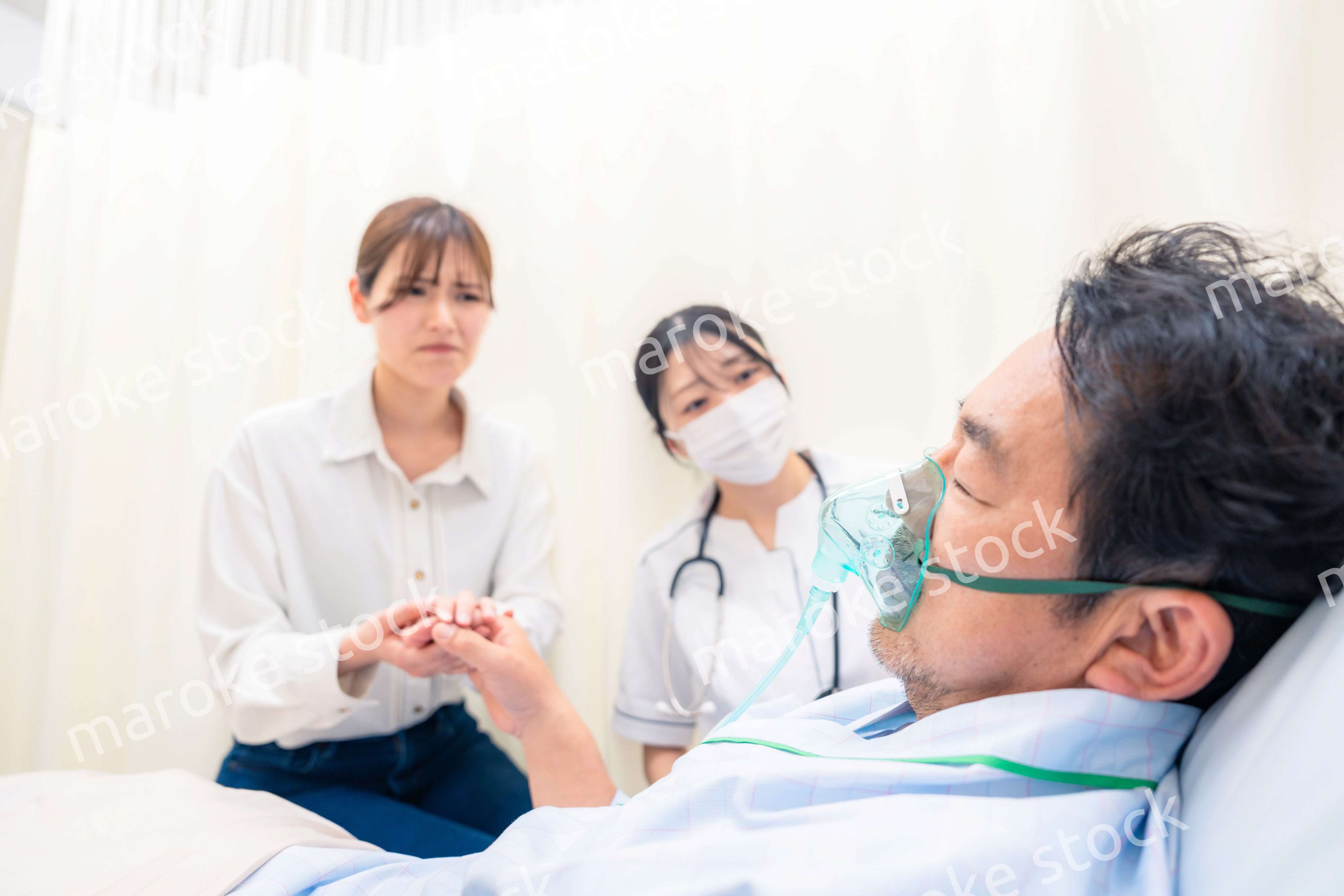 人工呼吸器をつけた家族のお見舞いをする若い女性