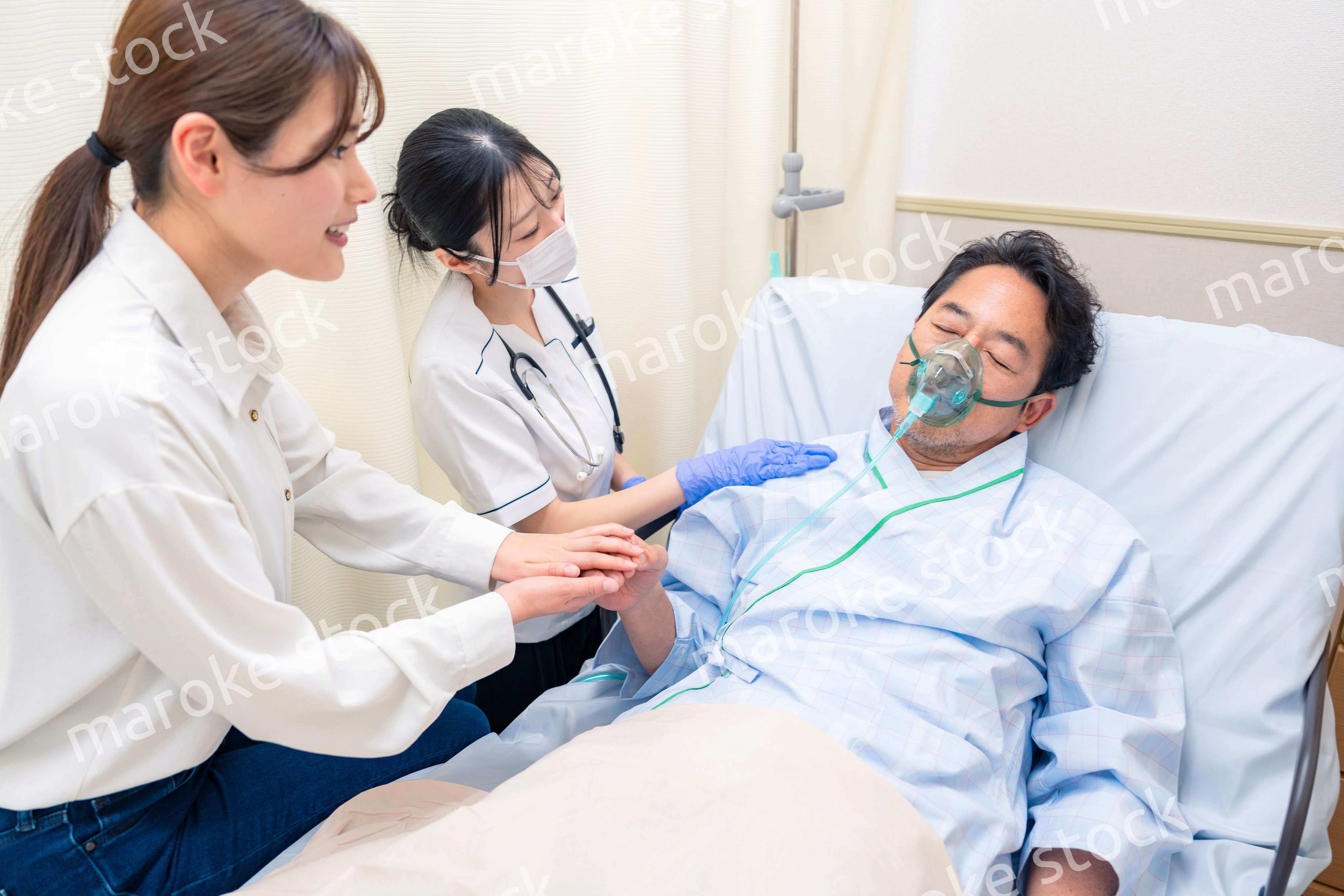 人工呼吸器をつけた家族のお見舞いをする若い女性